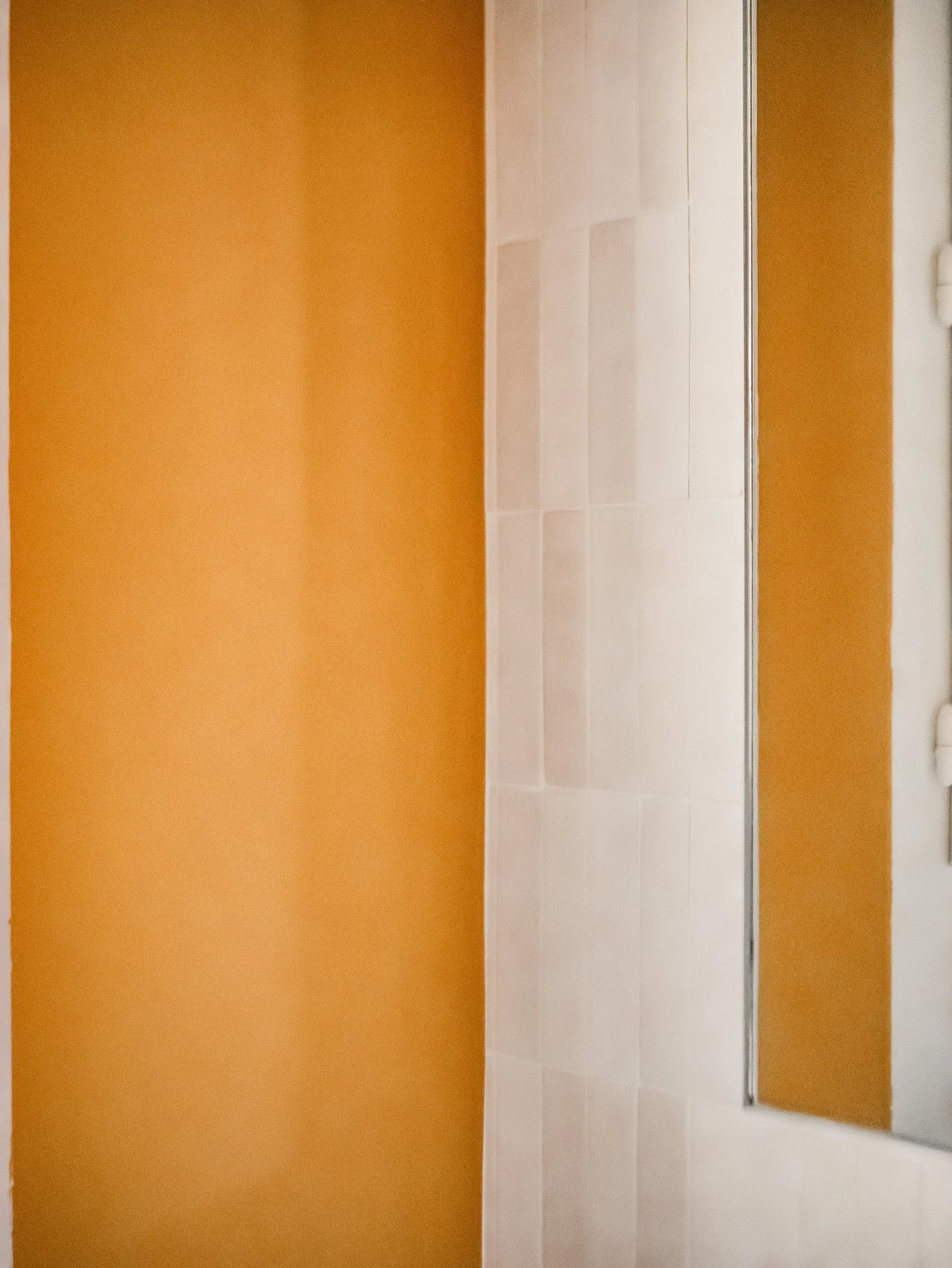 Rénovation d'un salle de bain dans un appartement ancien à Rouen. Meubles sur-mesure avec étagères et placards en bois foncé, douche à l'italienne et baignoire avec huisseries noires, peinture couleur cumin, miroir sur mesure avec zellige mural blanc