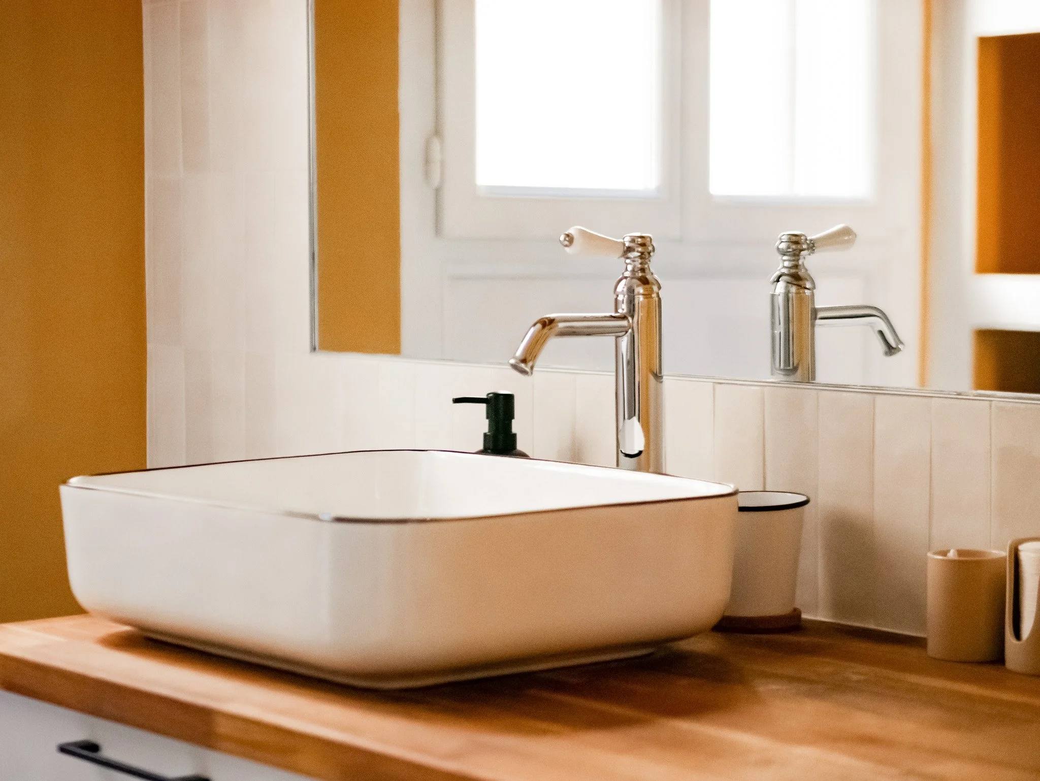 Rénovation d'un salle de bain dans un appartement ancien à Rouen. Meubles sur-mesure avec étagères et placards en bois foncé, douche à l'italienne et baignoire avec huisseries noires, peinture couleur cumin, miroir sur mesure avec zellige mural blanc
