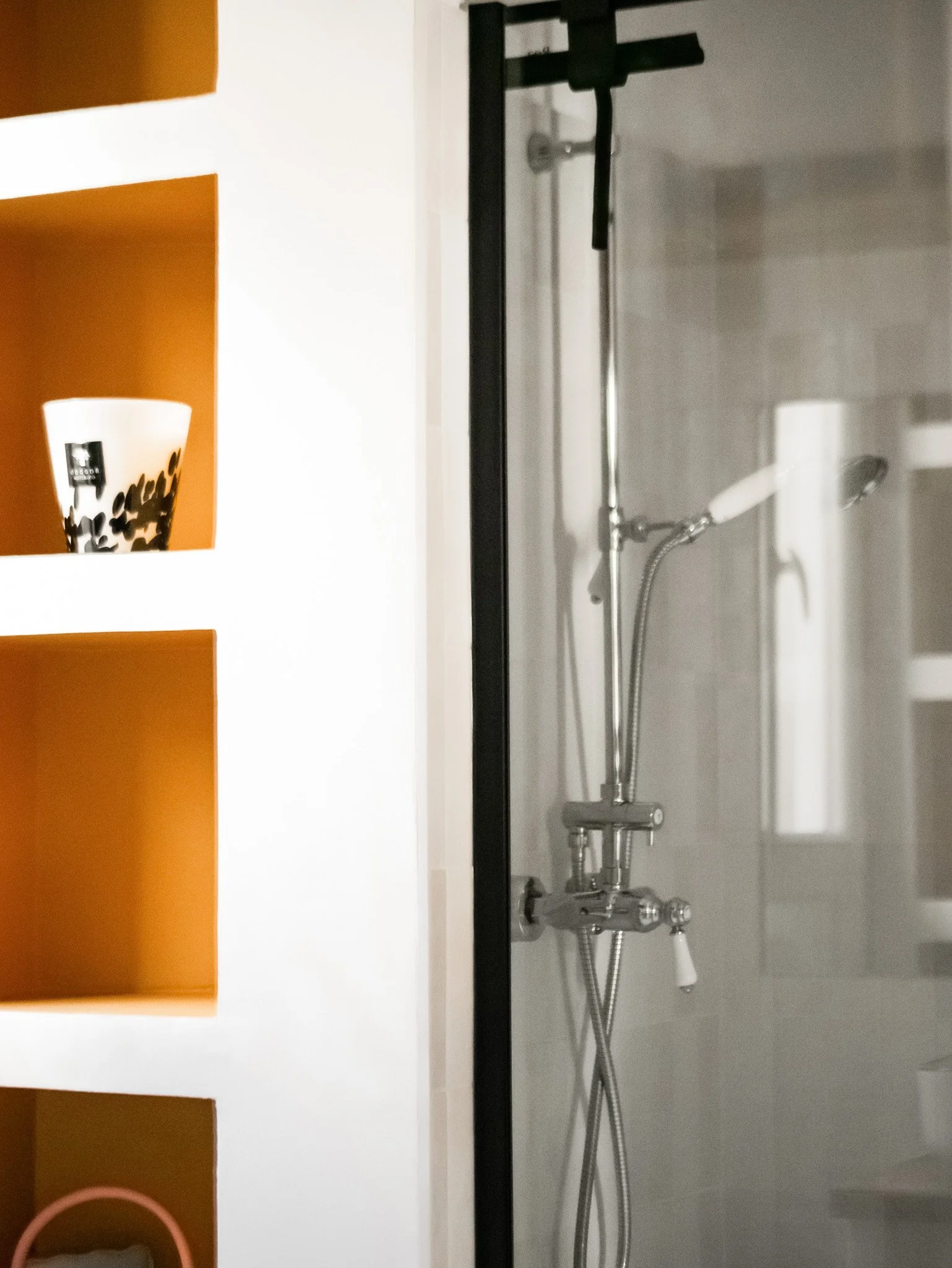 Rénovation d'un salle de bain dans un appartement ancien à Rouen. Meubles sur-mesure avec étagères et placards en bois foncé, douche à l'italienne et baignoire avec huisseries noires, peinture couleur cumin, miroir sur mesure avec zellige mural blanc