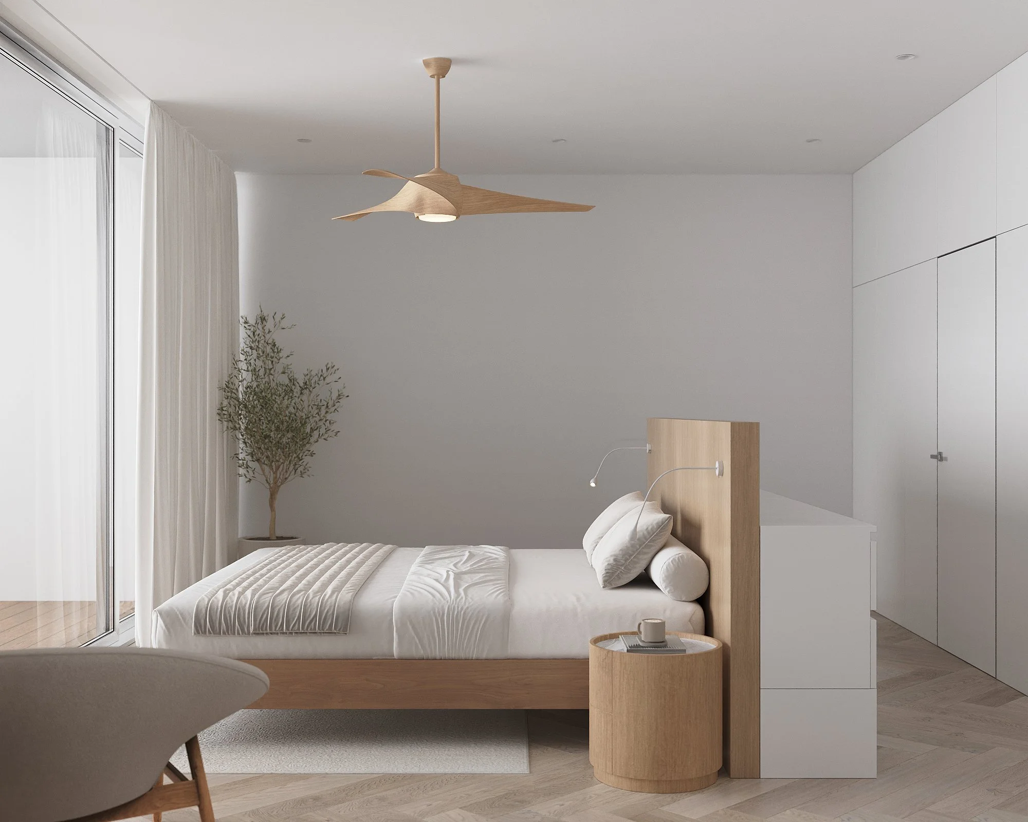 A minimalist bedroom with a wooden bed, white bedding, a small round wooden nightstand with a coffee cup, a beige armchair, a large window with white curtains, a potted plant, a wooden ceiling fan, white walls, and built-in white closets.