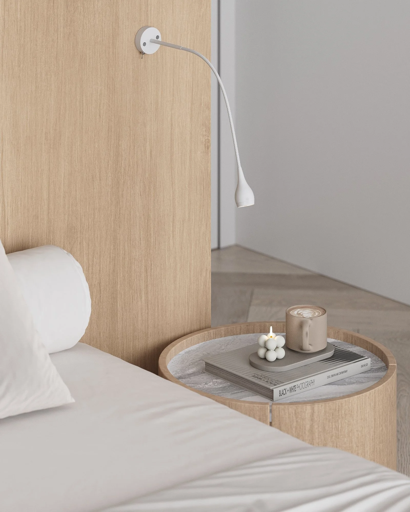 A white wall-mounted reading lamp hanging beside a wooden headboard next to a bedside table with a book, candle, and decorative object.