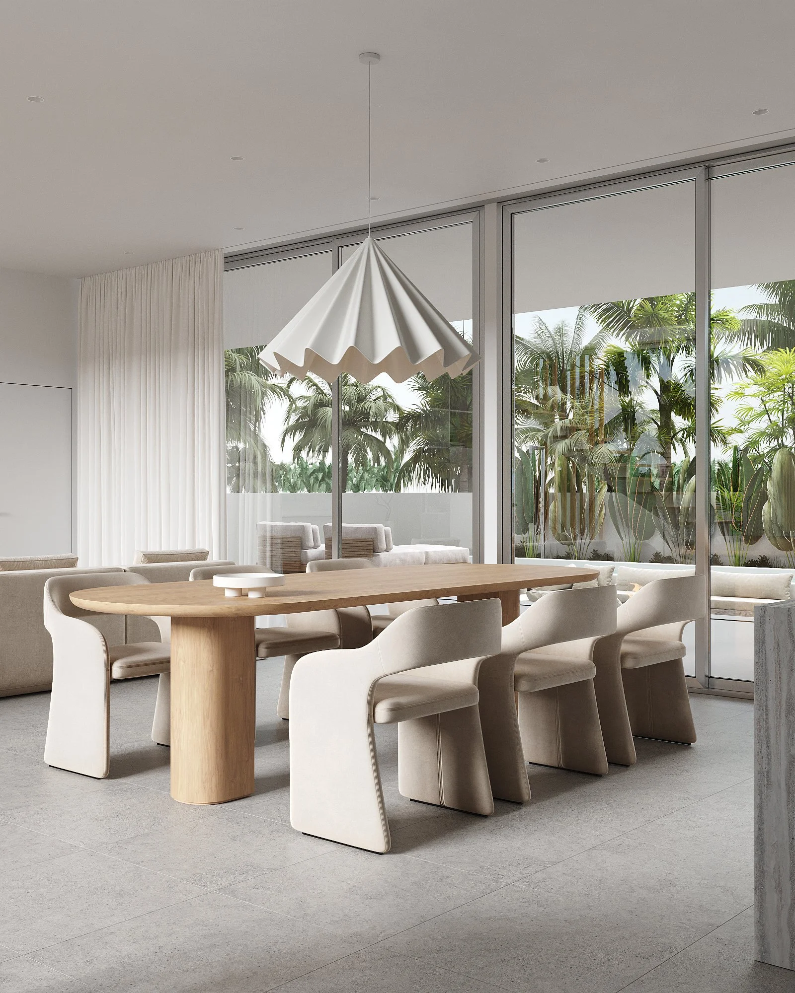 Modern dining room with a wooden table, white chairs, large hanging light, and glass walls with views of greenery outside.