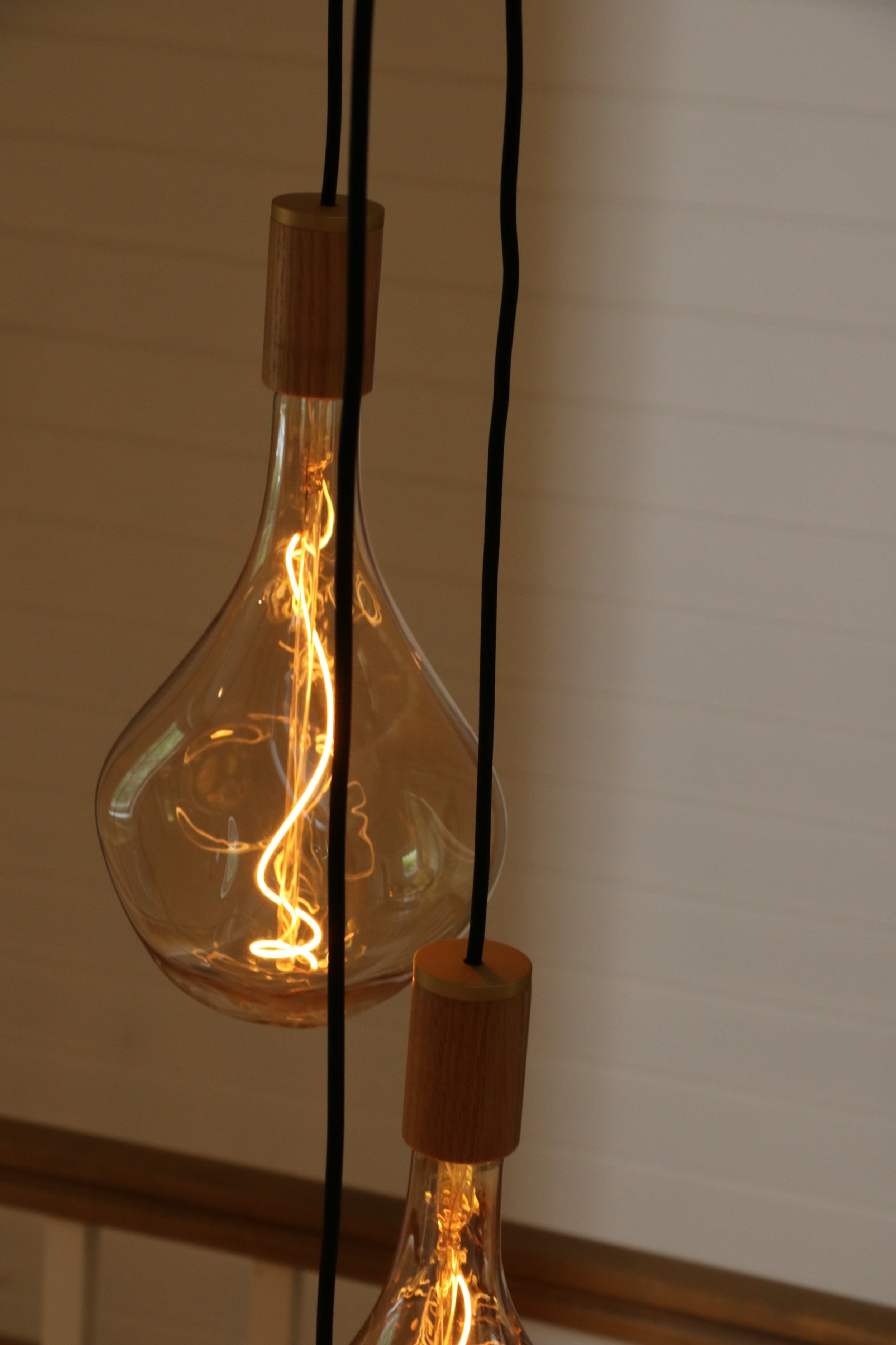 Twee hangende Vonoroi pendellampen met houten fitting en zichtbare gloeidraden.