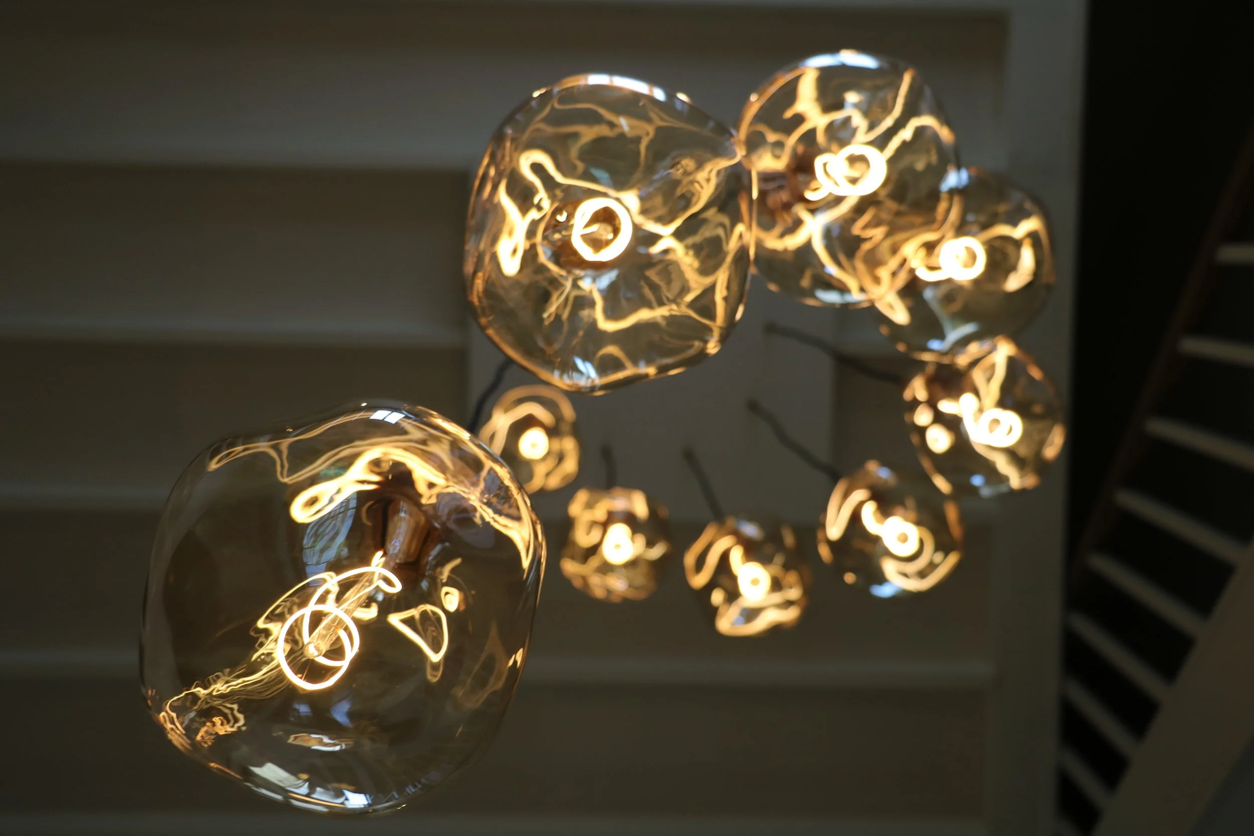 Hanglampen met glazen bollen en warme sfeervolle gloed, binnenshuis in een open trappenhal.