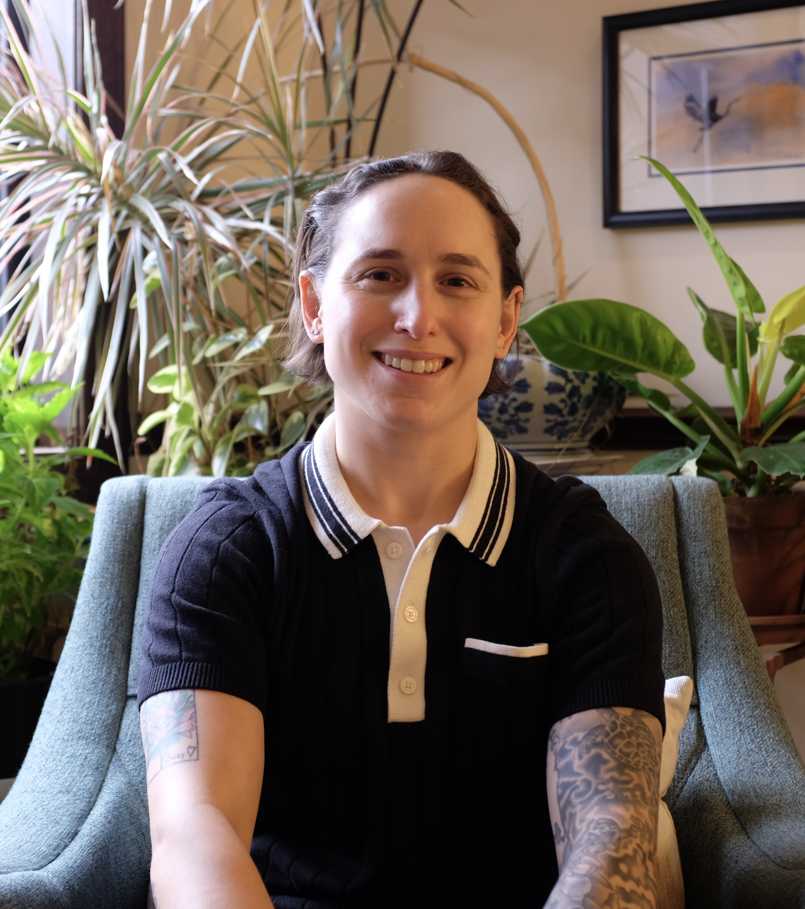Jess Stern, LPC, EMDR and trauma therapist at Alleviate Trauma, smiling in a chair surrounded by plants