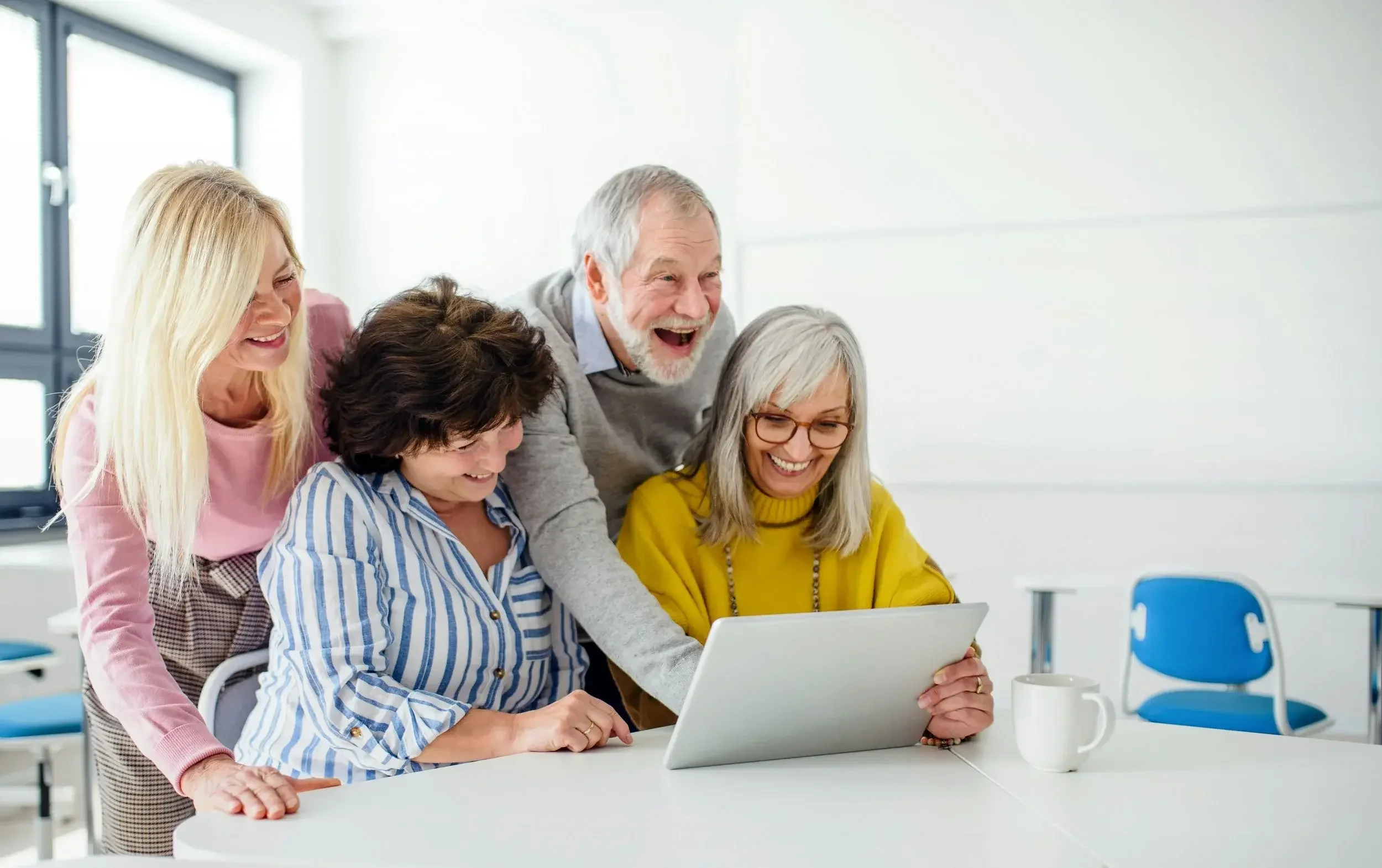 Gruppe von Menschen über 50 arbeitet gemeinsam am Laptop in einem Workshop