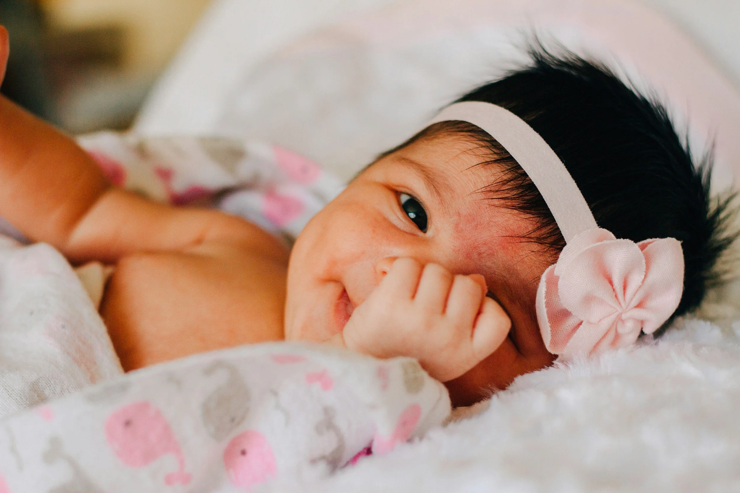 Baby girl with a pink bow after a gentle calm birth using hypnobirthing