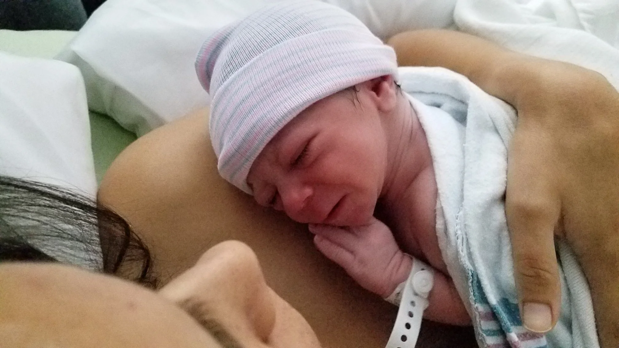 Close-up of newborn Pea resting against her mom's chest, fingers near her mouth, after a calm Hypnobirthing birth