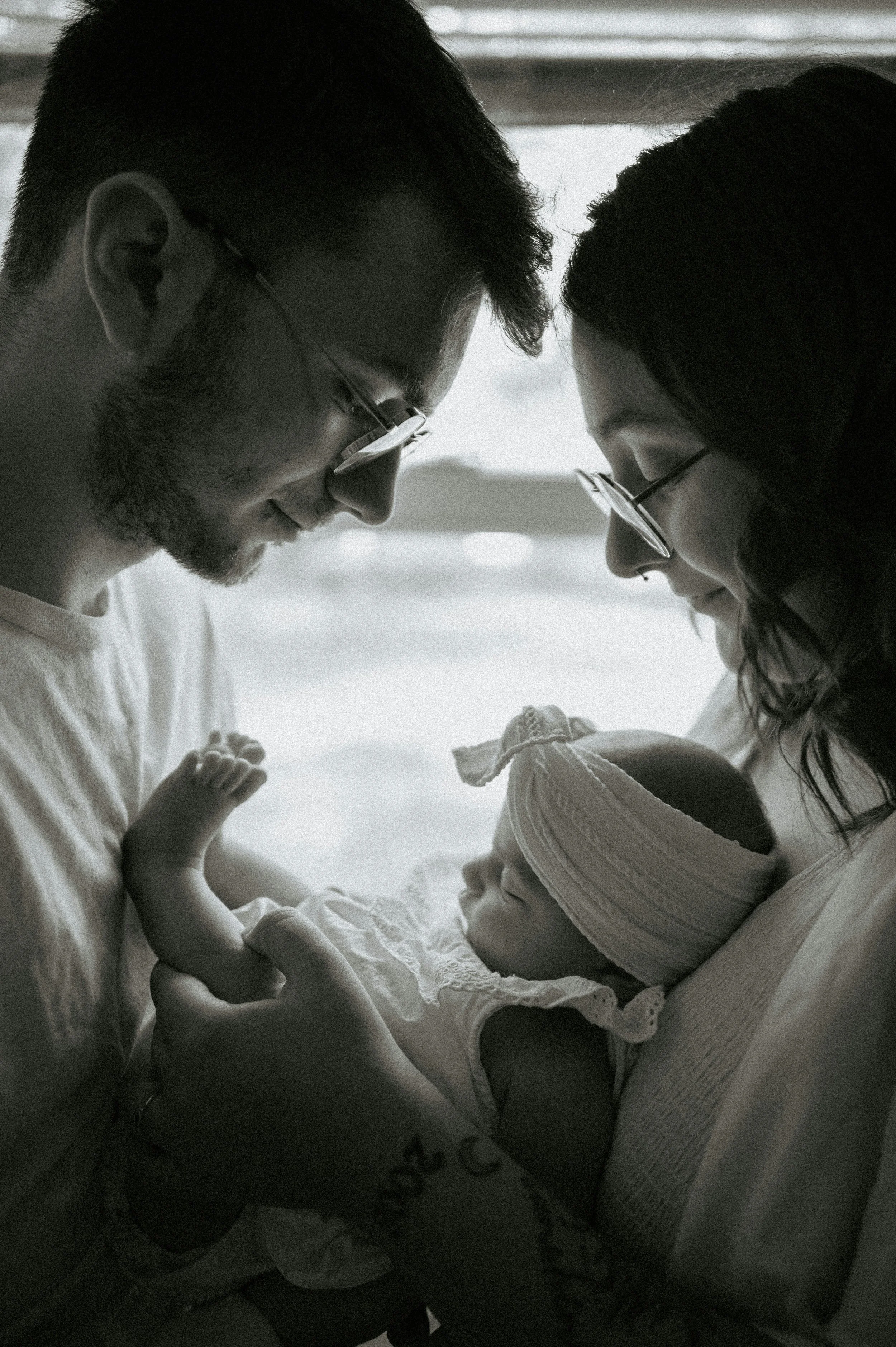 Black and white photo of new parents gazing at their newborn, birth support from Birthing by Nature