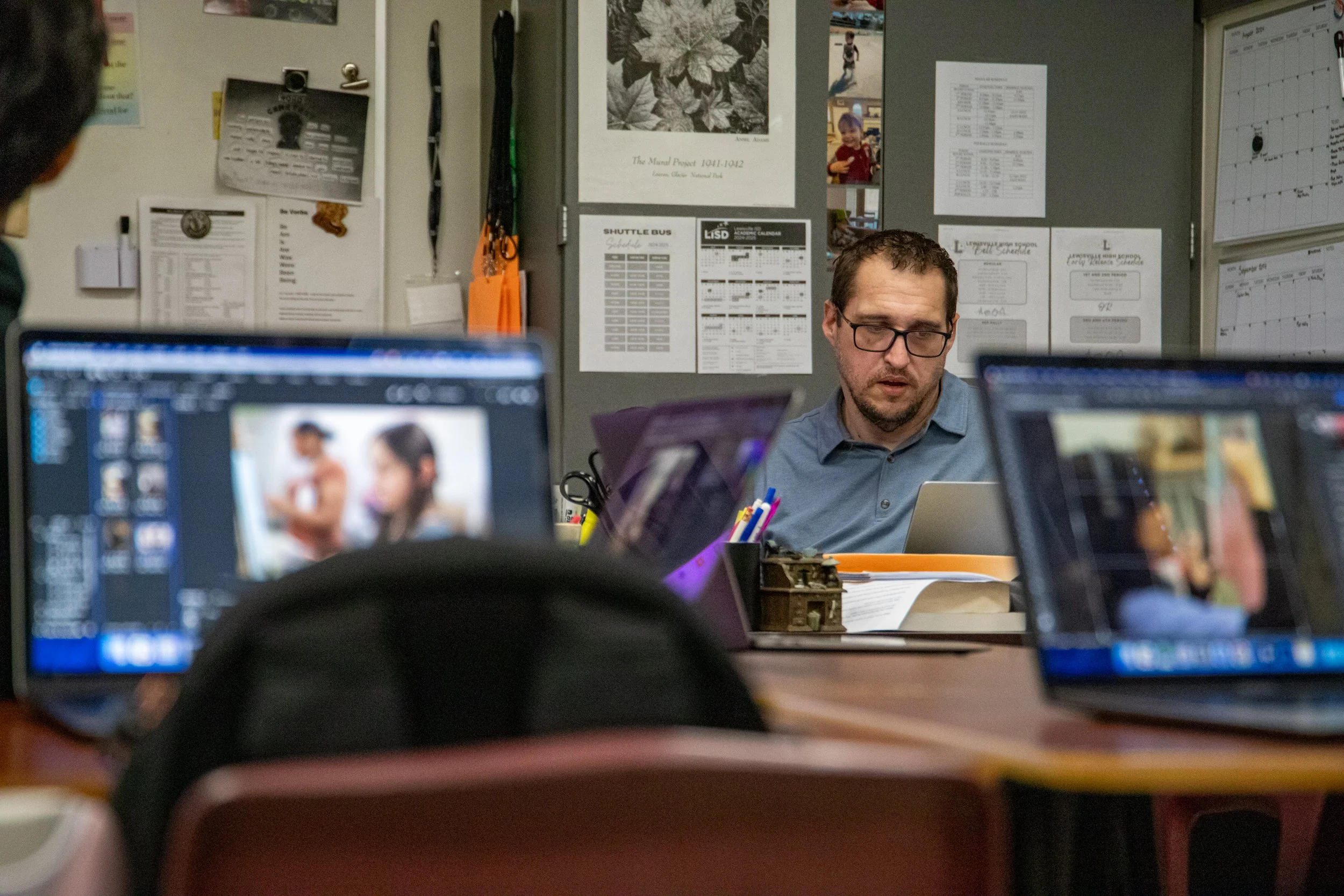 Hale waits for students to finish editing their photos during the Photojournalism I class while responding to emails. He first demonstrated how to edit photos by checking the levels and curves, and now he expects students to do the same. 