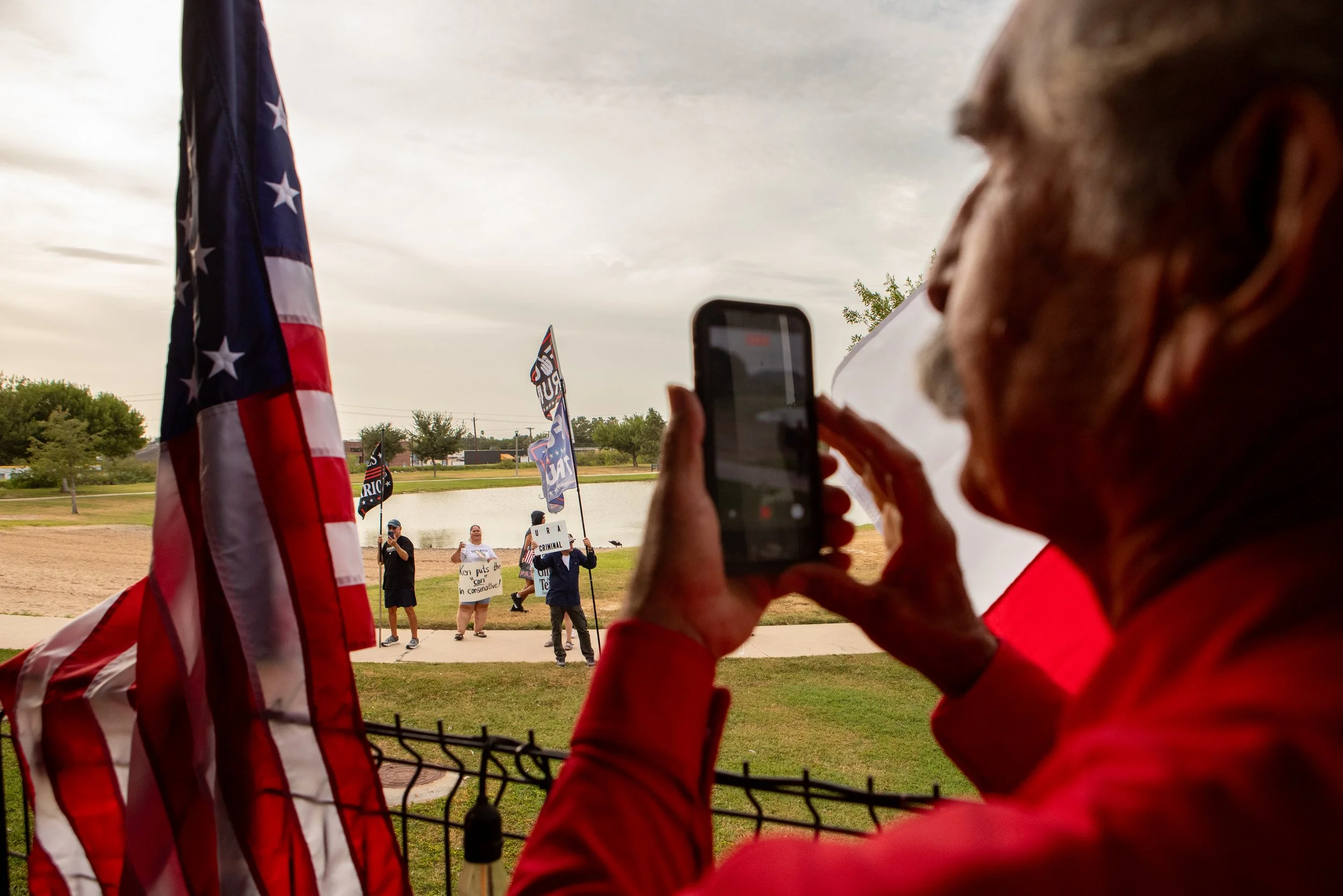 A supporter of Ken Paxton records protesters outside of the "Rally in the Valley" event in McAllen, TX, on July 14, 2026.