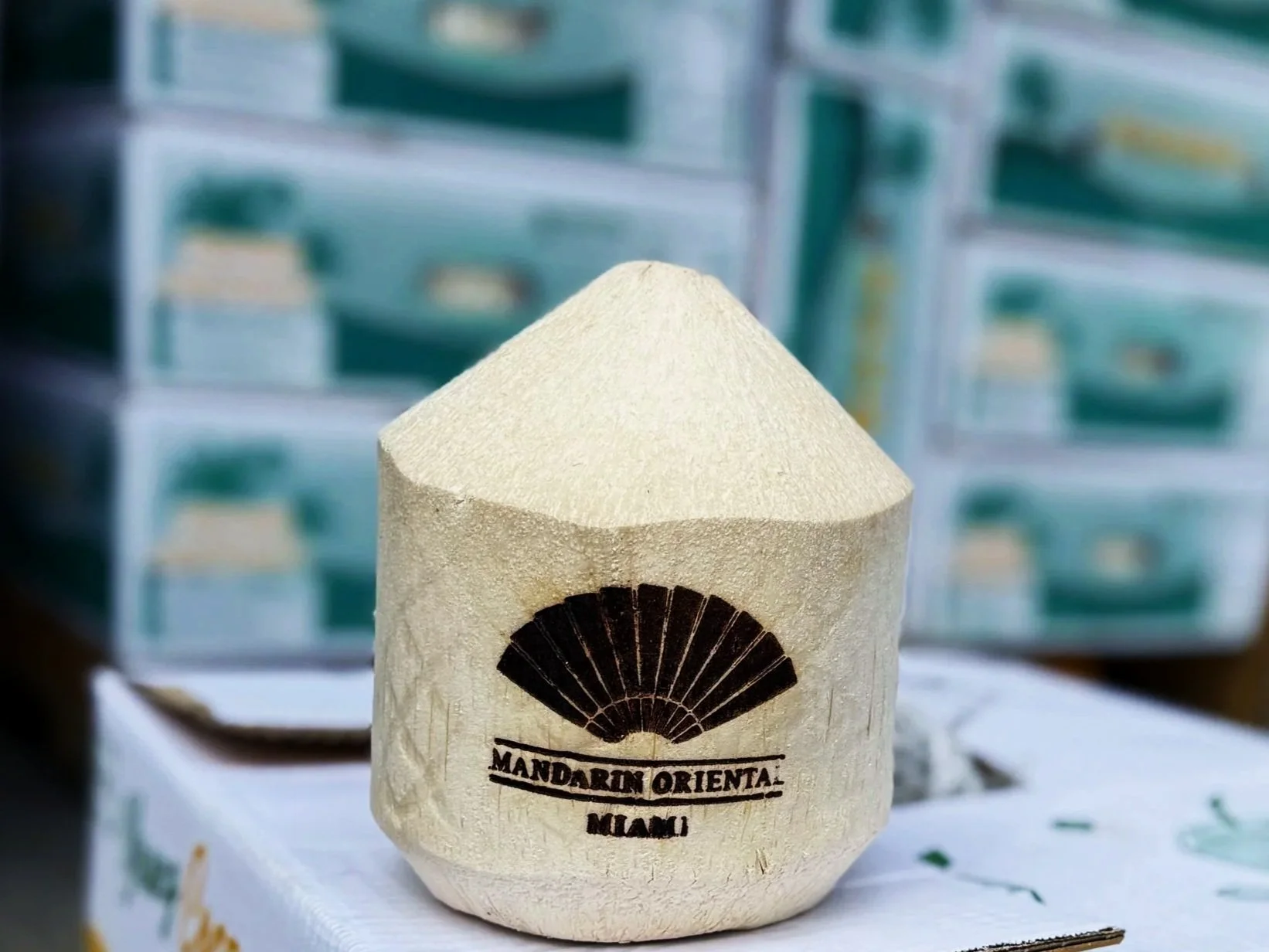Cream-colored custom coconut with a black fan design and text that reads "MANDARIN ORIENTAL MIAMI."