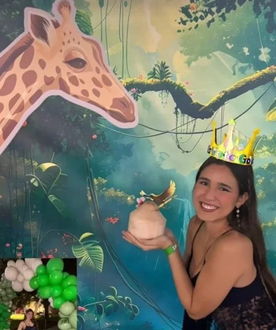 Young woman wearing a paper crown and holding a personalized coconut in her hand, with a jungle-themed backdrop featuring a giraffe illustration.