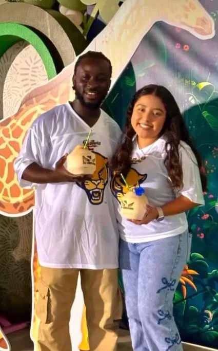 Two people smiling and holding yellow bowls with jungle animal designs, standing in front of a colorful jungle-themed backdrop.