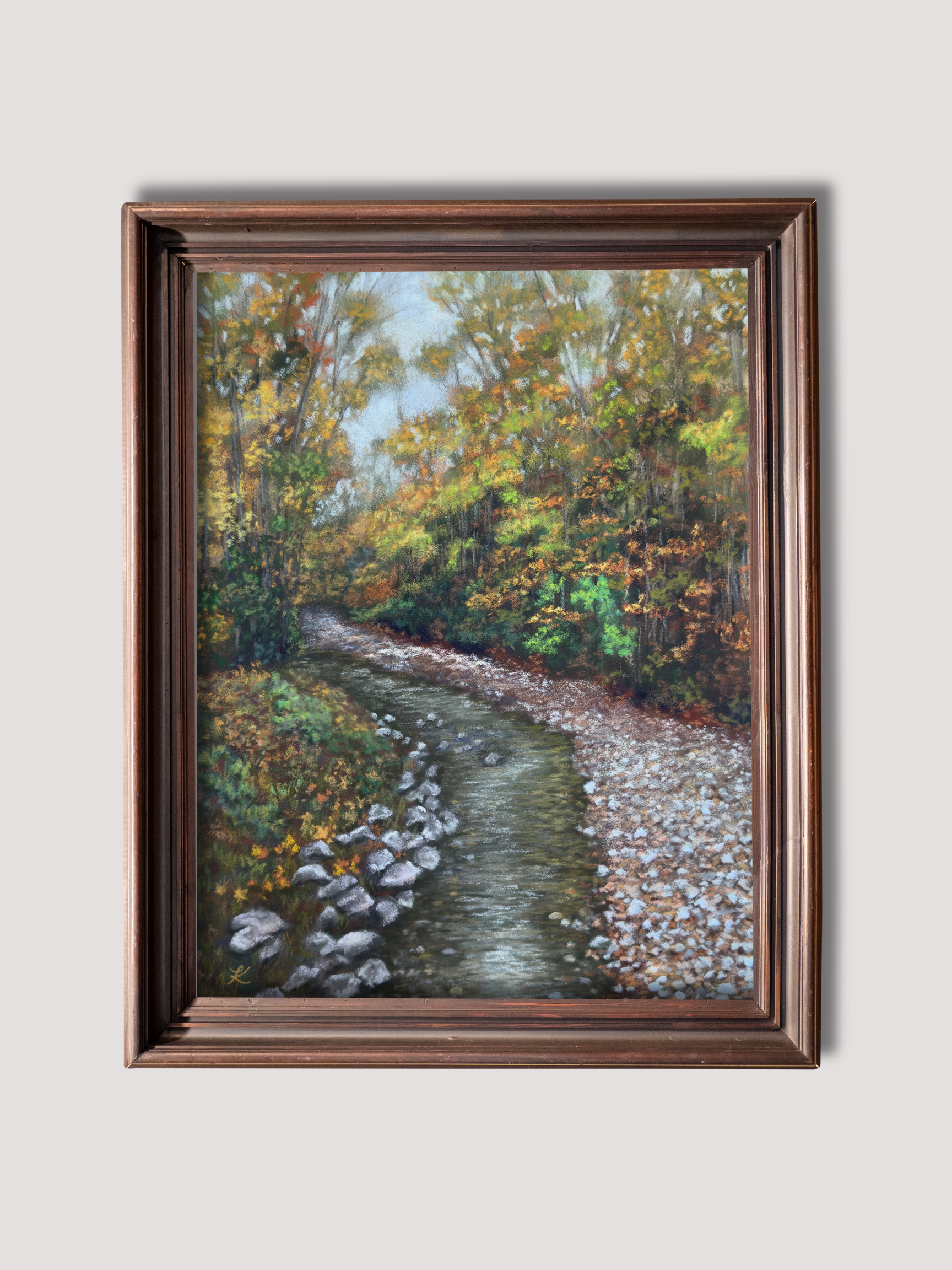 Framed painting of Vermont fall stream surrounded by trees filled with leaves of green, gold, and orange