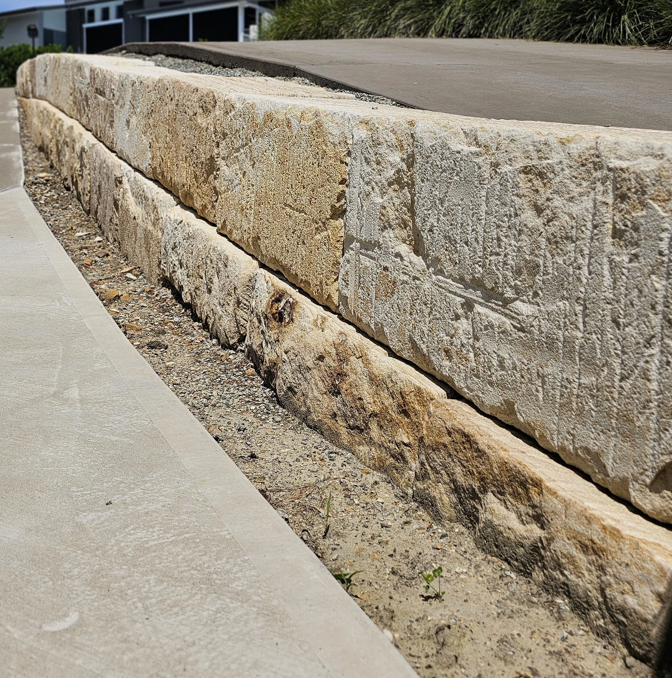 Close-up of a stone retaining wall with a concrete sidewalk.