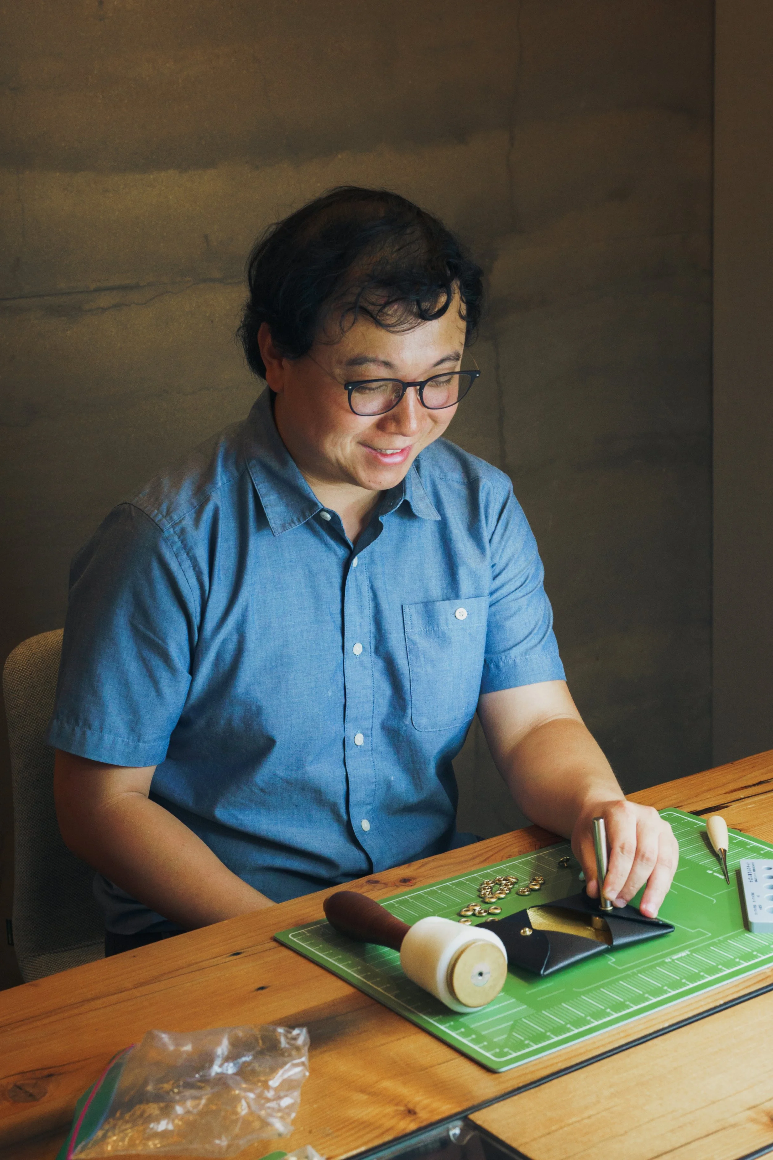 Tom Cheng, founder of Cuirated, leathercrafting at his workbench
