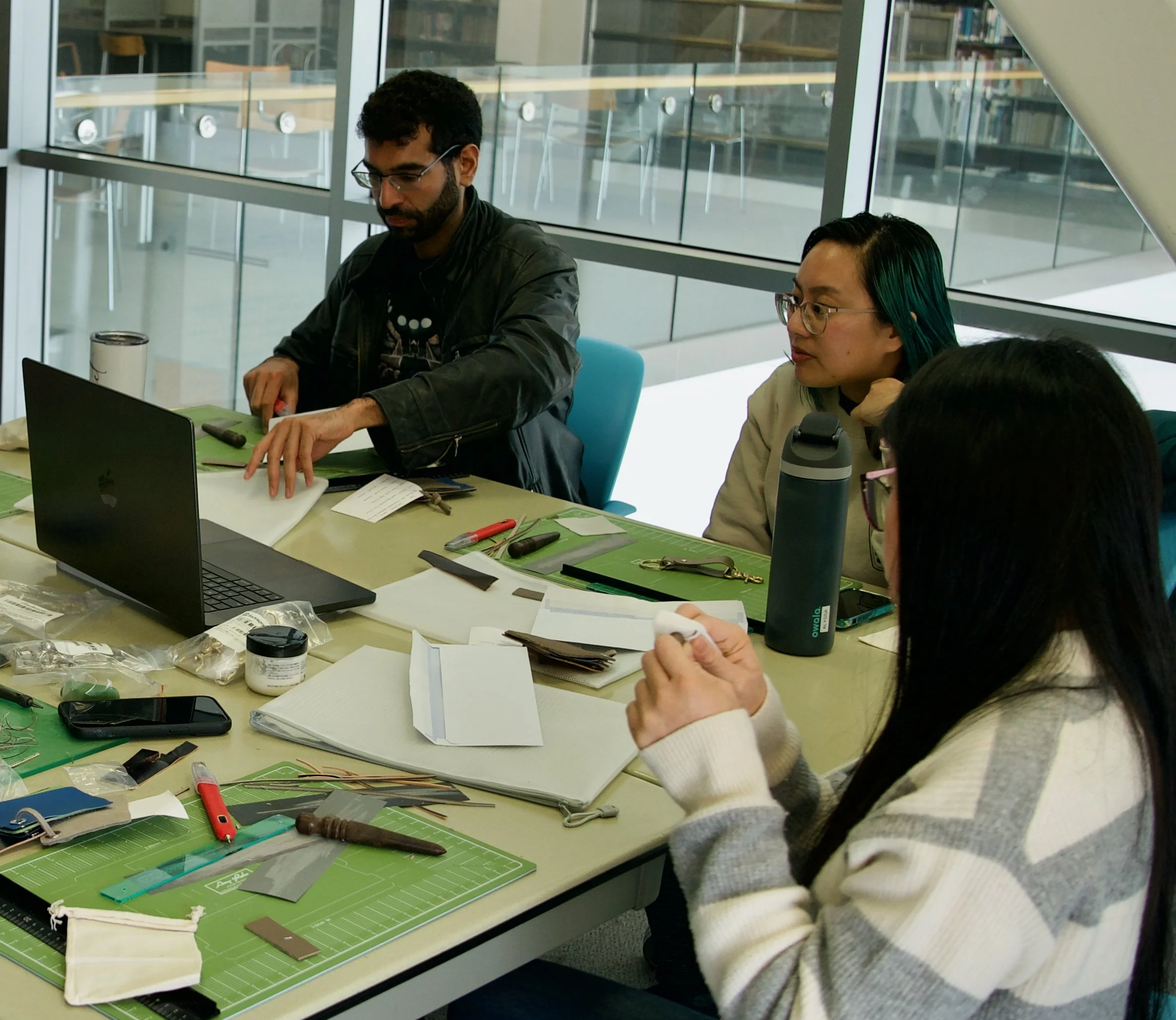 Team members collaborating at a modern office table during a hands-on corporate leathercrafting workshop in the Bay Area.