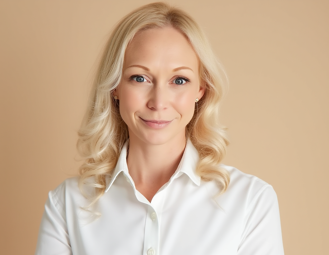 A woman with blonde hair wearing a white blouse smiling at the camera against a beige background.
