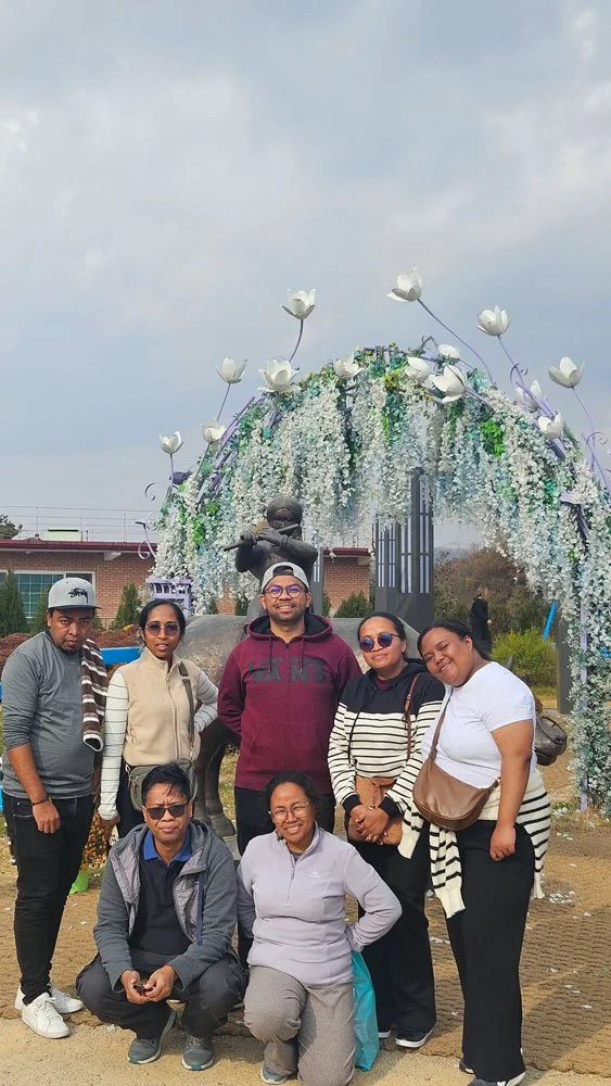 Madagascar travelers on a private tour visiting Tongilchon (Unification Village), traditional Korean village setting, scenic mountains in the background, high-resolution travel photography