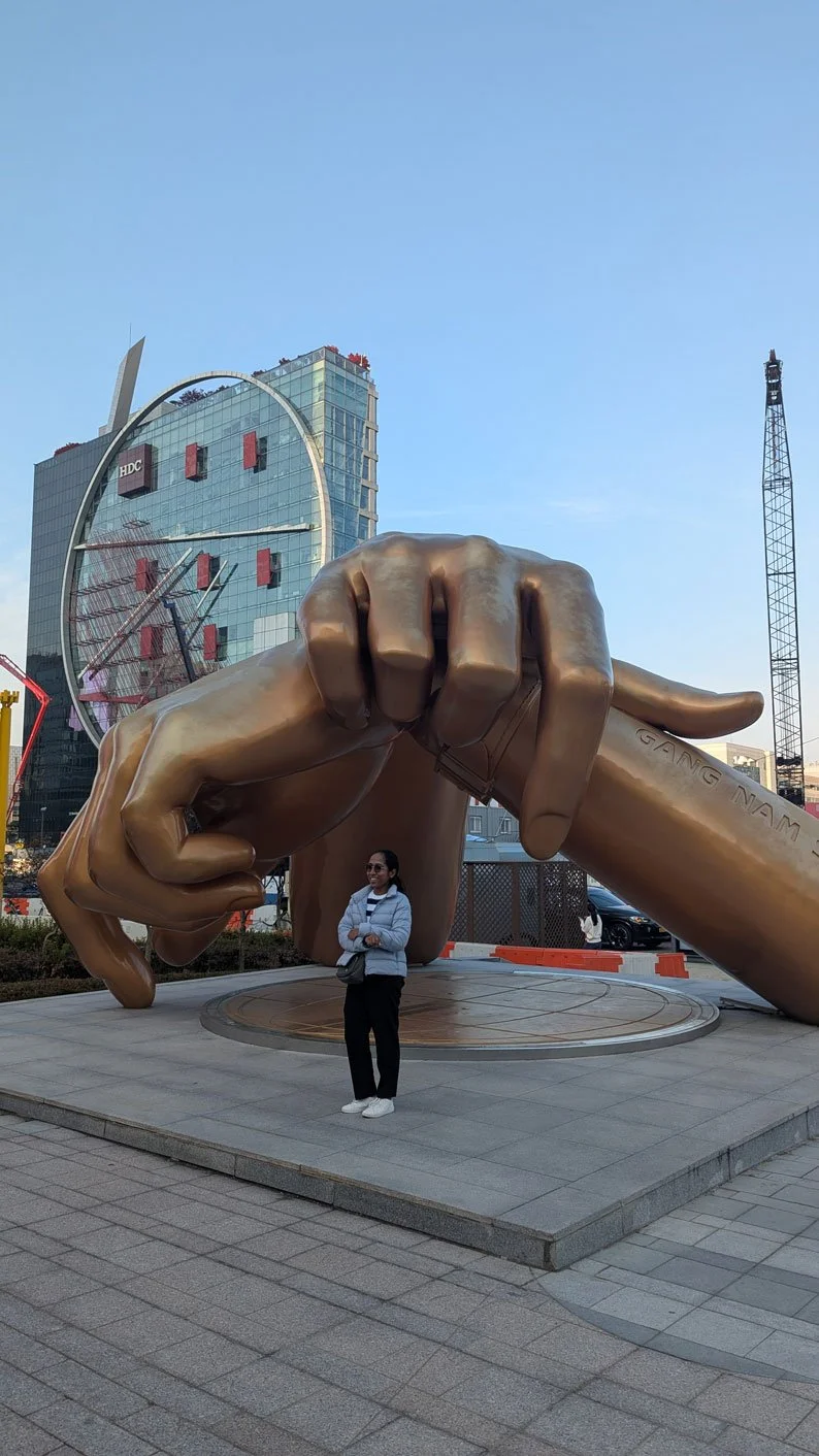 Madagascar tourists on a private tour posing with the Gangnam Style statue in Seoul, vibrant city background, sunny day, cultural sightseeing experience, high-resolution travel photography