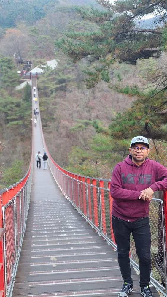 Madagascar family private tour crossing Gamaksan Suspension Bridge, lush green mountains, sunny day, vibrant travel photography