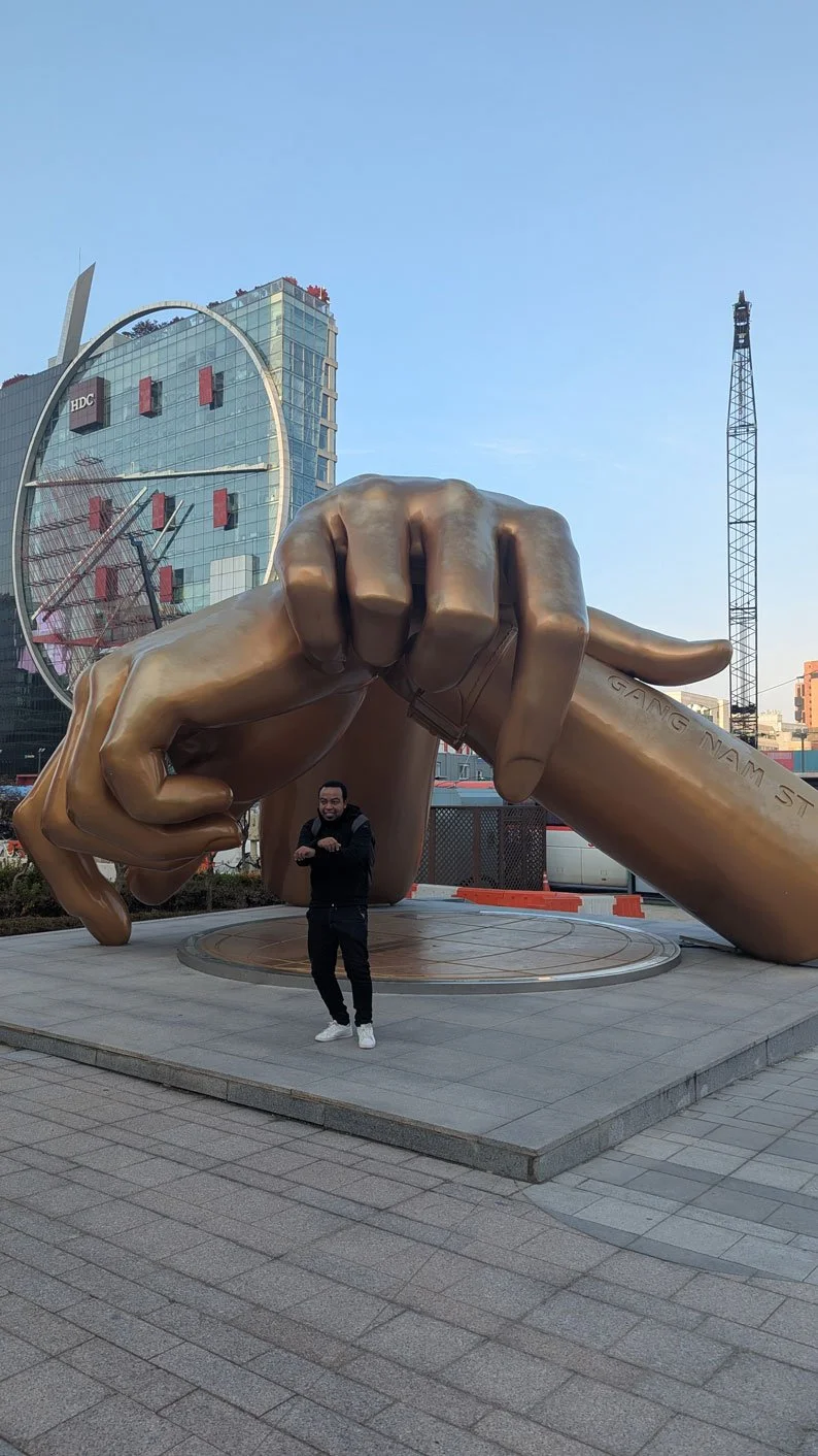 Private tour for Madagascar travelers at Gangnam Style statue, Seoul street scene, colorful urban environment, excited tourists taking photos, realistic style, professional travel image