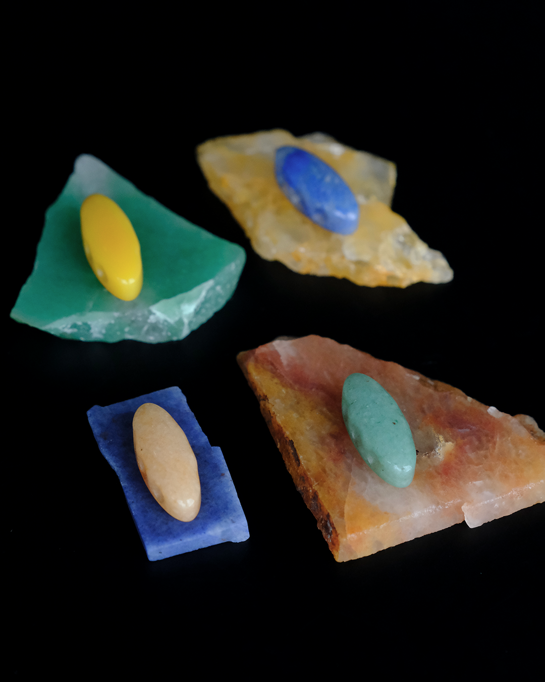 A collection of aventurine stones on a black background with laser-cut aventurine beads in corresponding colors.