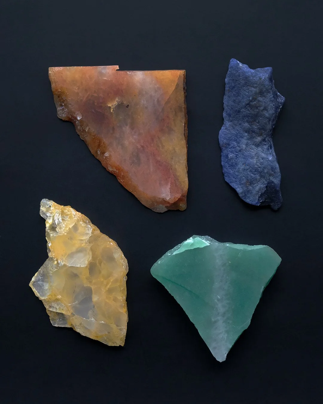 Four colorful aventuine slabs on a black background: a large brownish-red aventurine, a blue aventurine, a yellowish translucent aventurine, and a green aventuine.