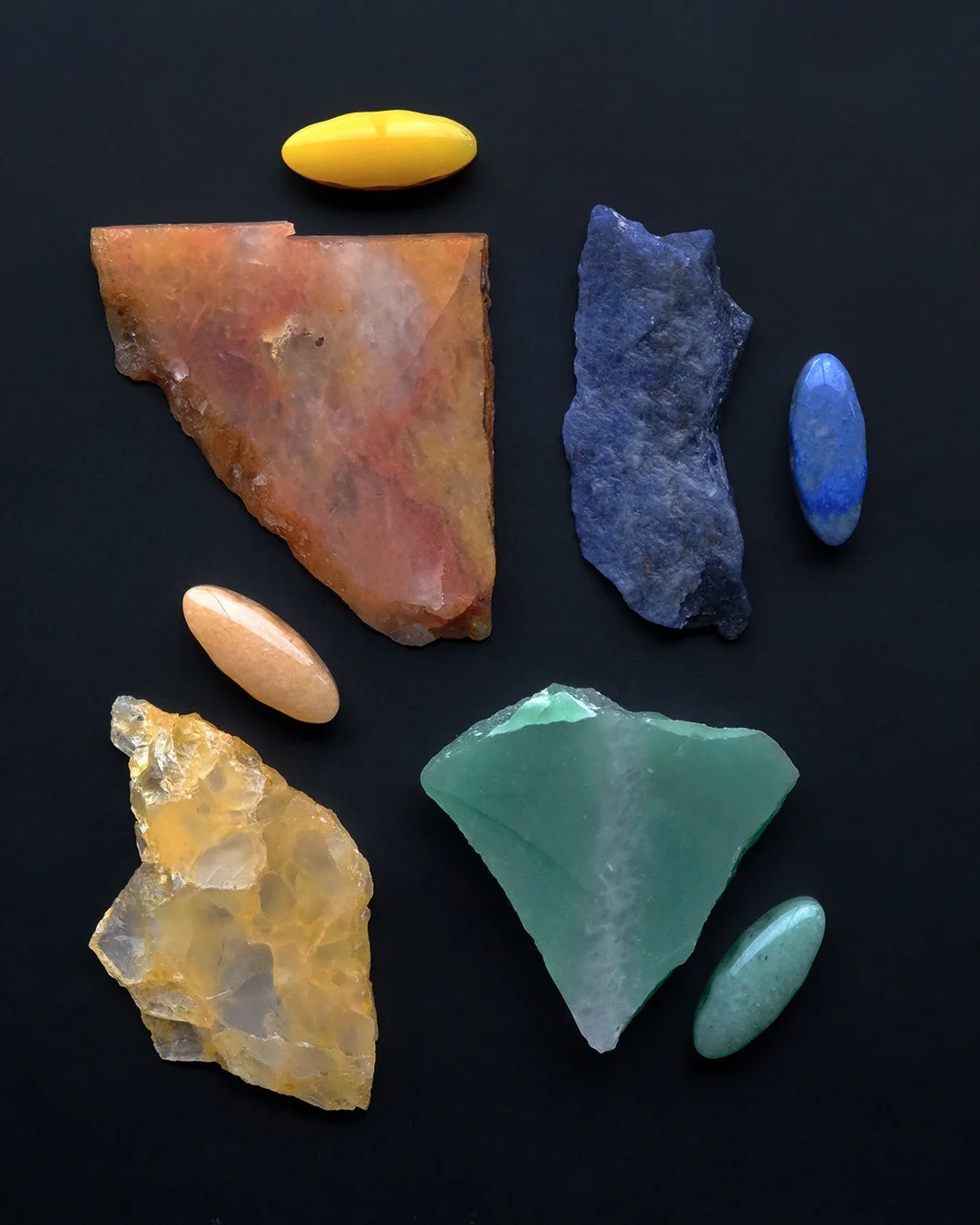 A collection of various colorful aventurine slabs on a black background, including laser-cut aventurine beads in corresponding colors.