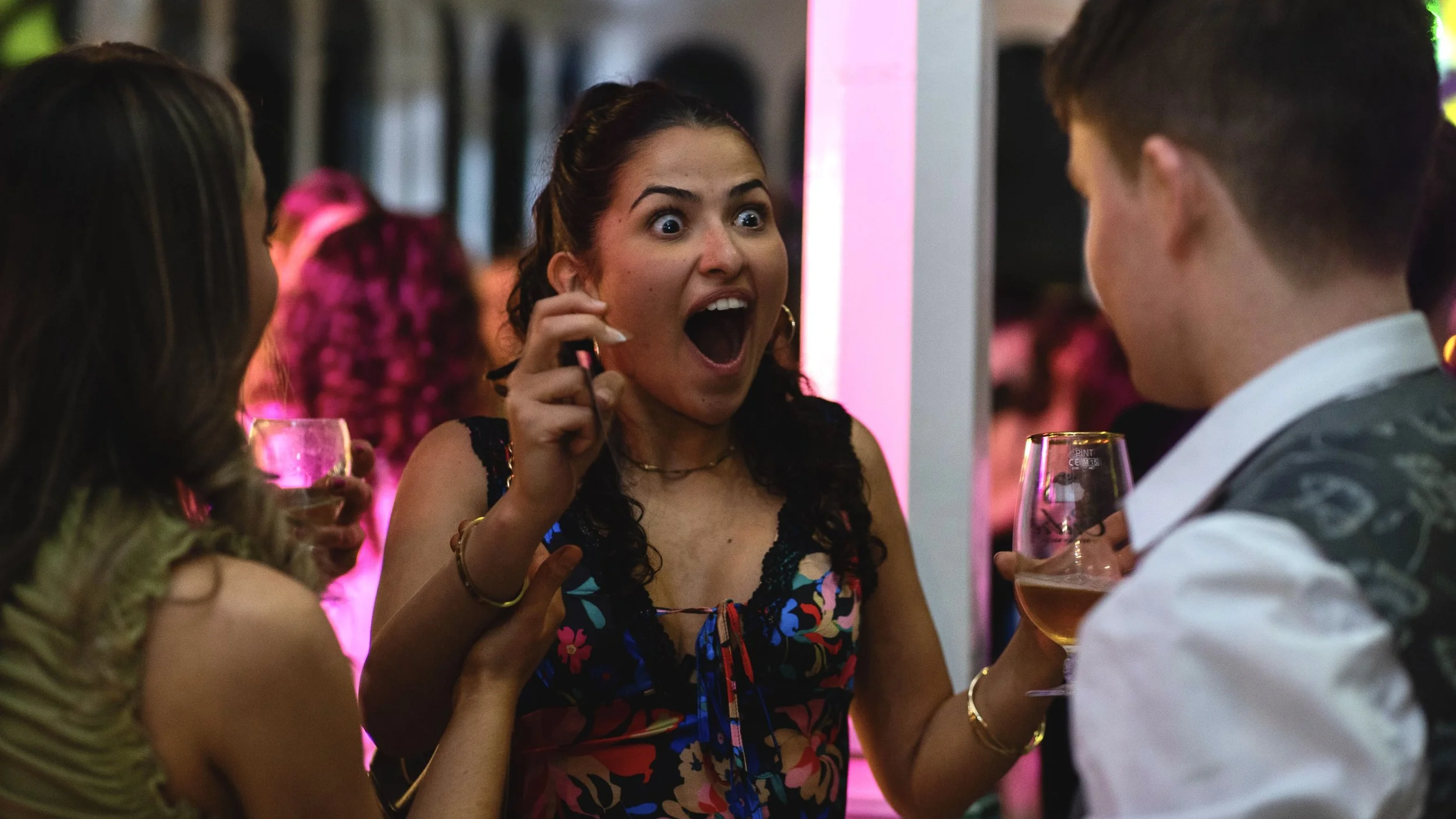 Group of people at a party, one woman reacting with excitement to magic Dan performing an amazing trick. 