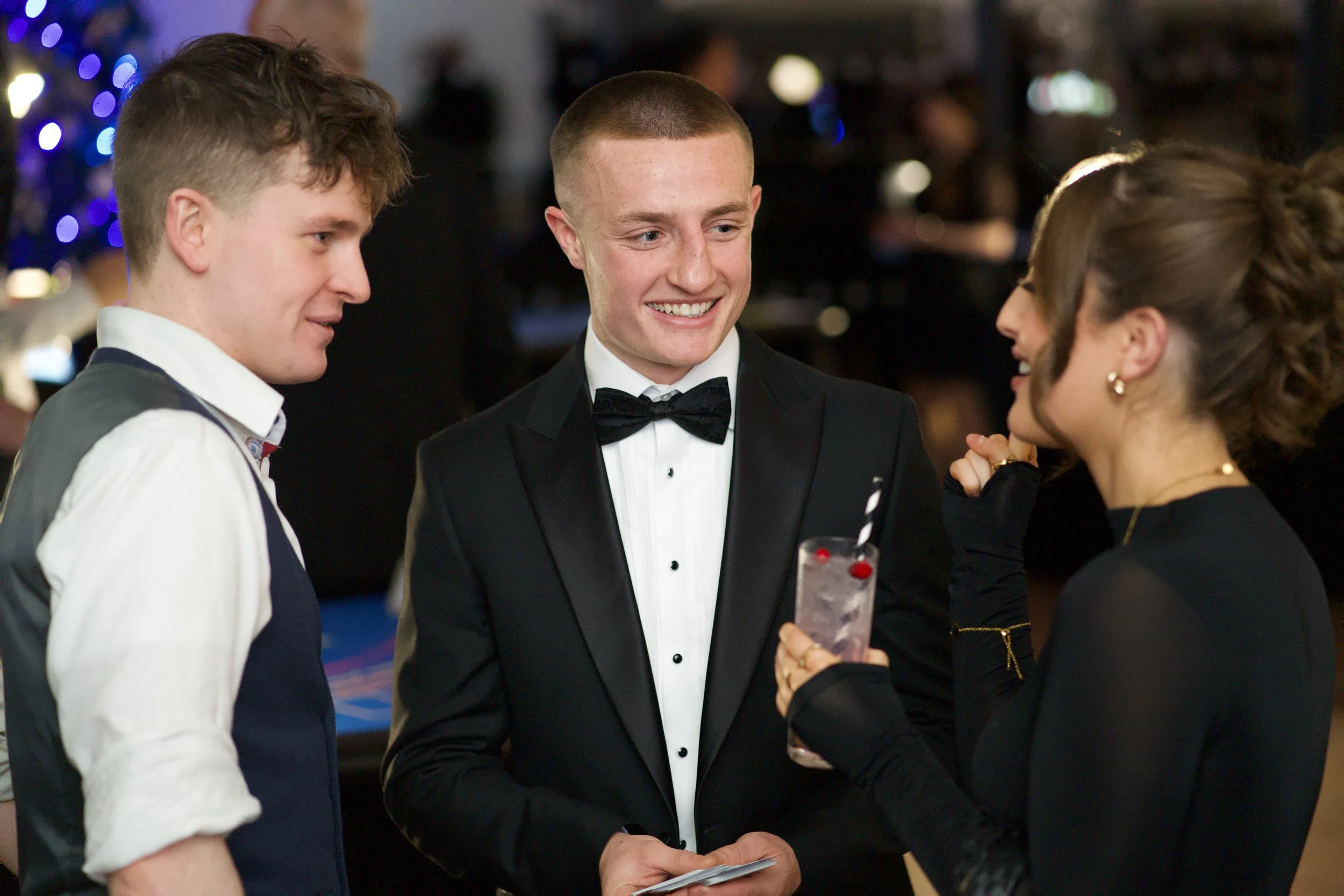 Three people in formal attire smiling and chatting at an event. They are reacting to amazing magic!