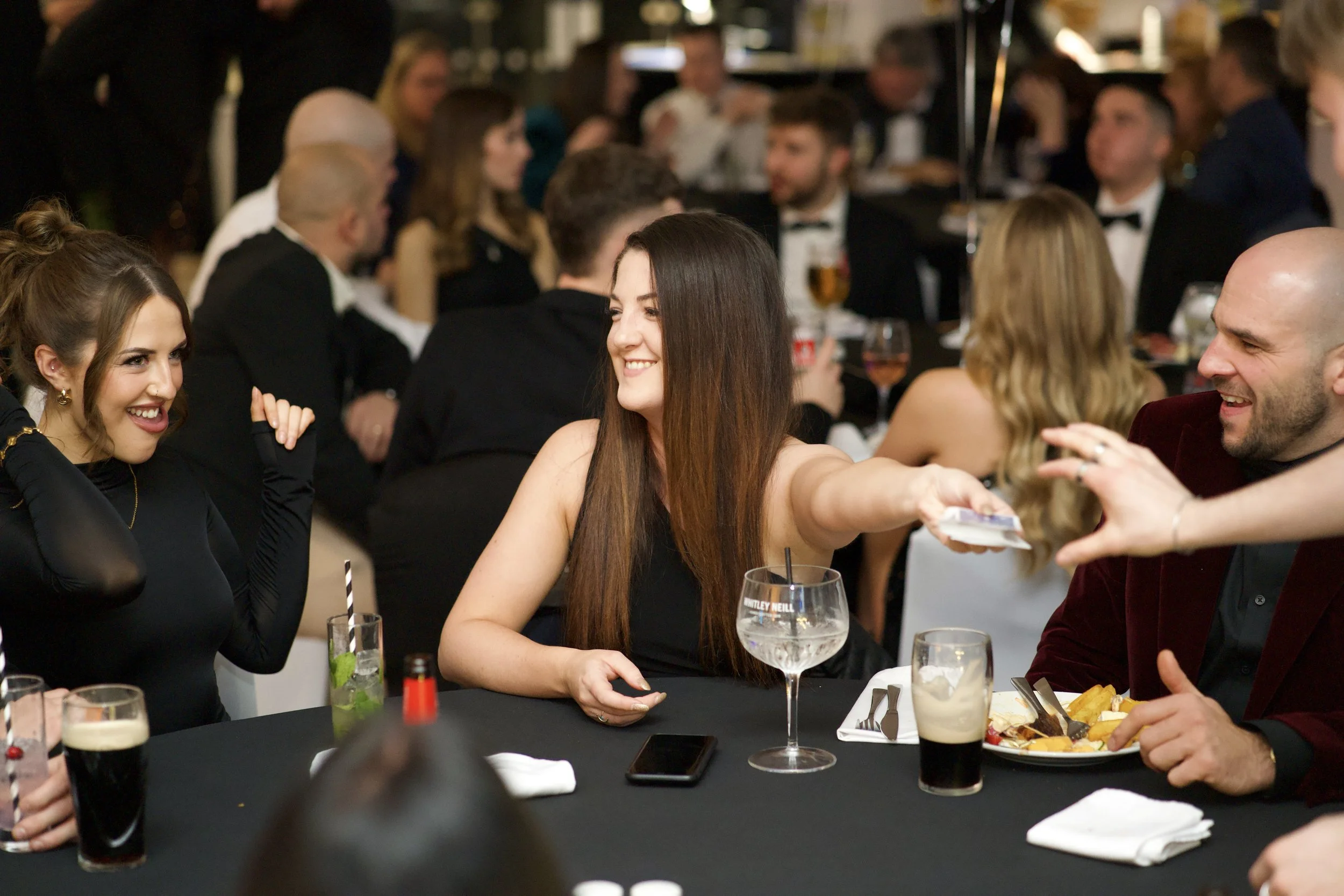 Group of people seated at a formal event, sharing and laughing around a table having just witnessed Manchester Magician Daniel Maze