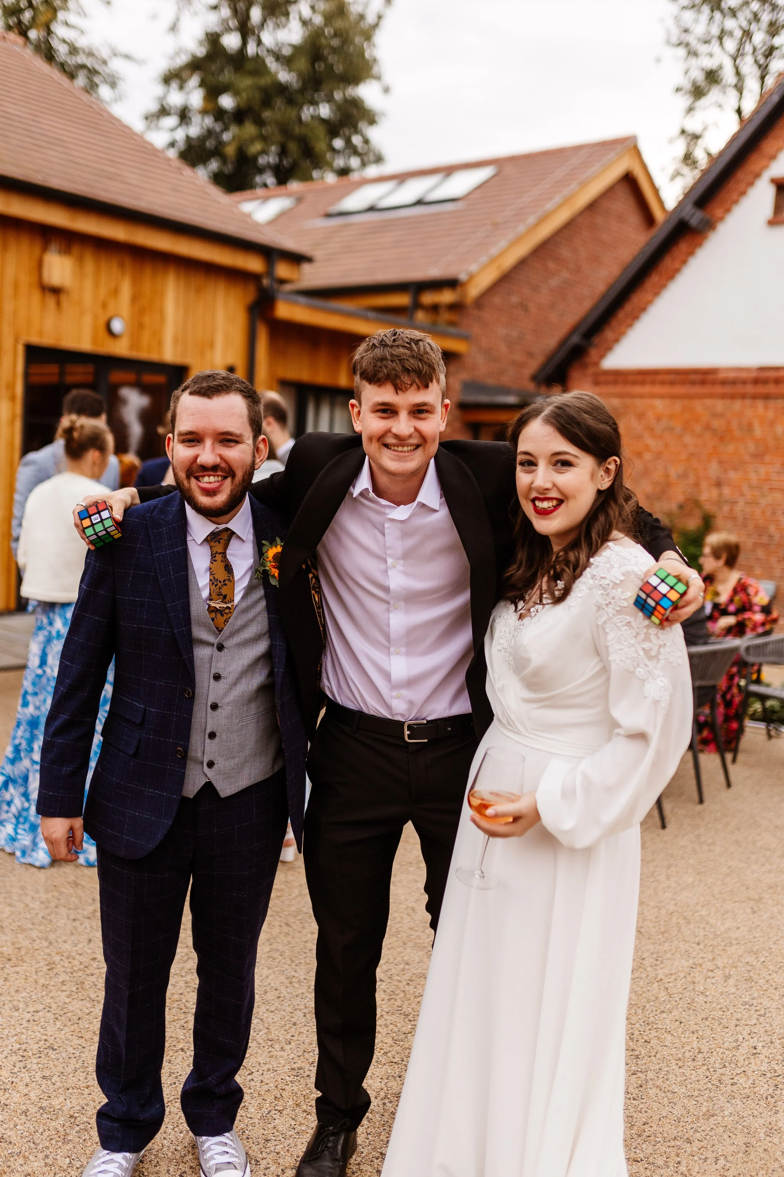 Wedding couple smiling with Daniel Maze magician outside, with Rubiks Cubes in hand. 