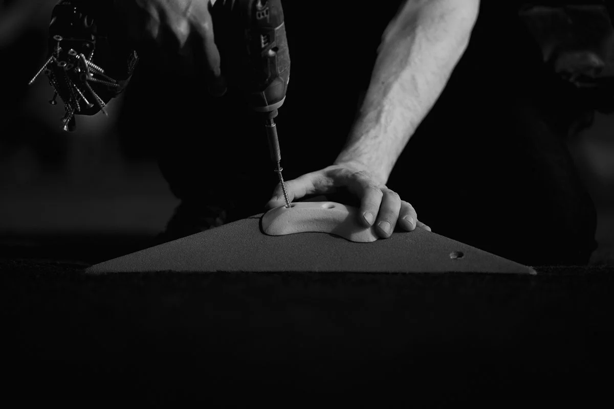 A routesetter screwing a crimp on a volume