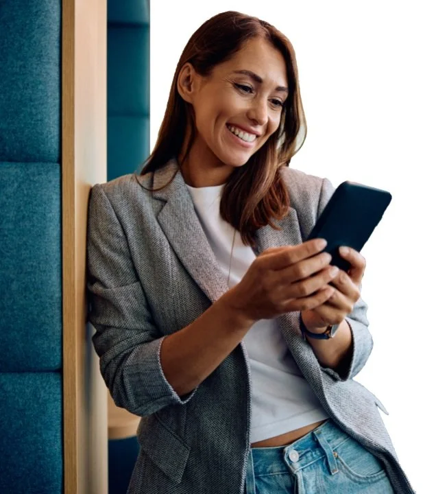 A smiling real estate agent in a blazer checking her phone