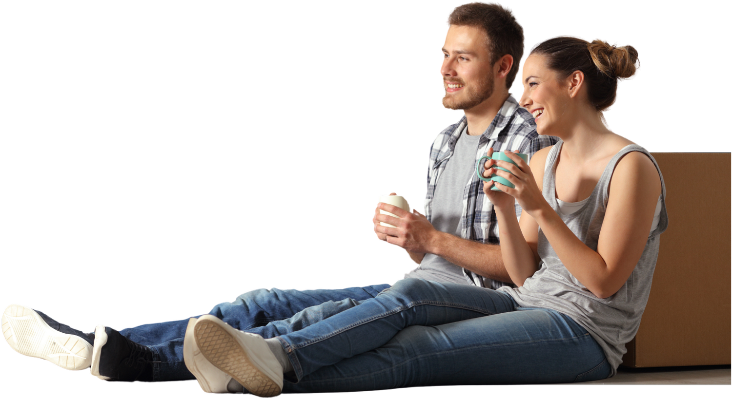 A smiling couple sitting on the floor of their new home with coffee mugs, next to moving boxes
