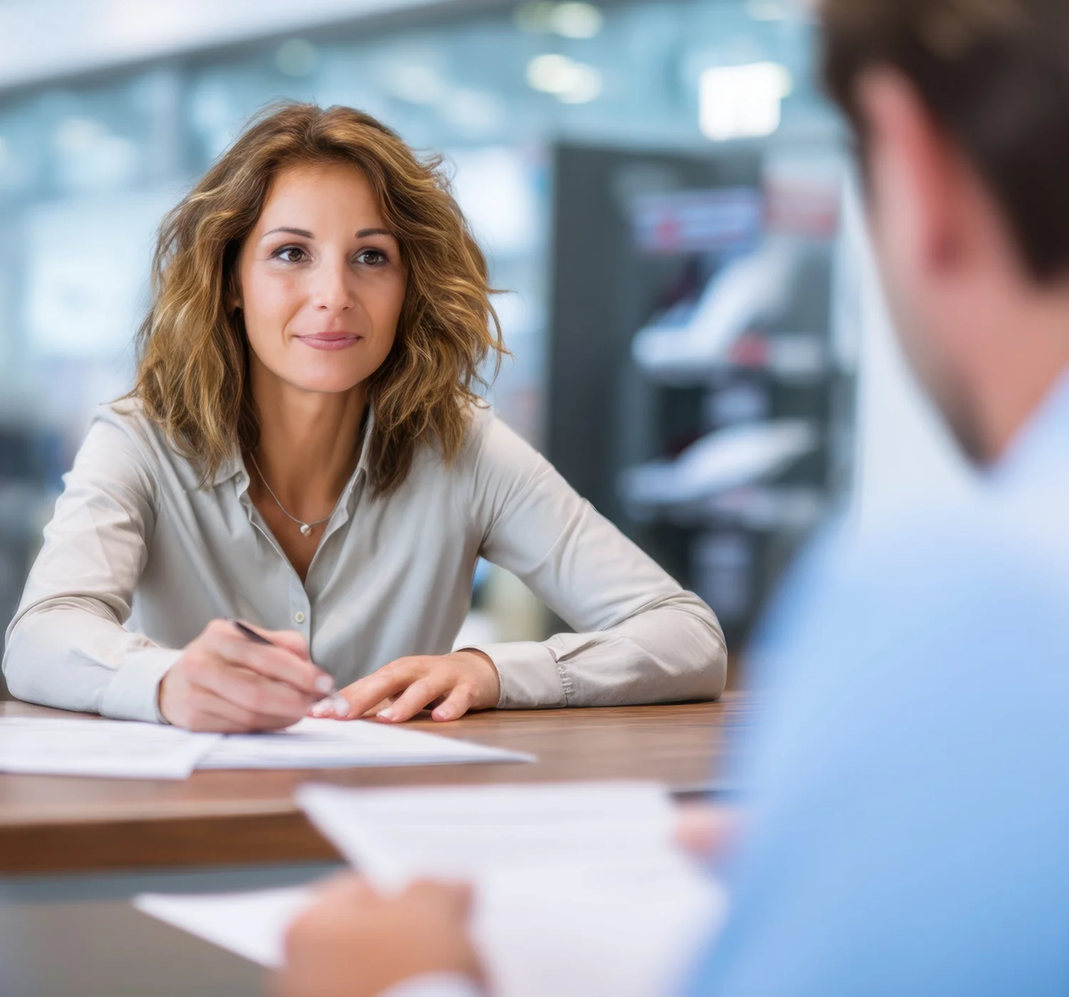 A woman reviews and signs loan paperwork across the desk from her loan officer