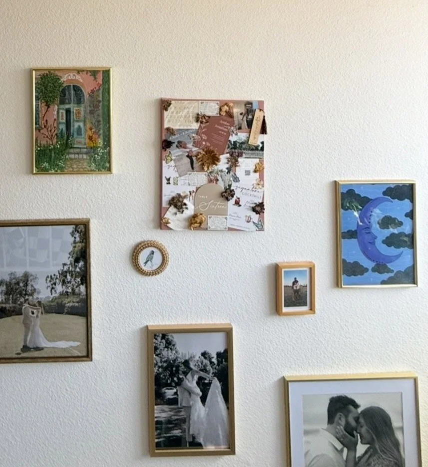 A wall decorated with various framed photos, artwork, and a small round decorative piece, arranged in a casual gallery style.