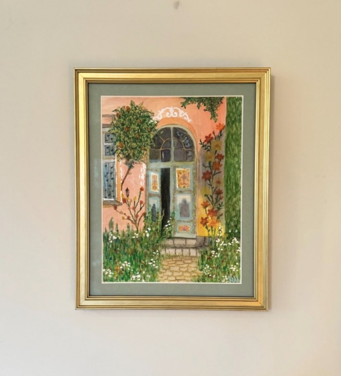 Colorful painting of a house entrance with a pink wall, window, door, greenery, and flowers, framed in gold.