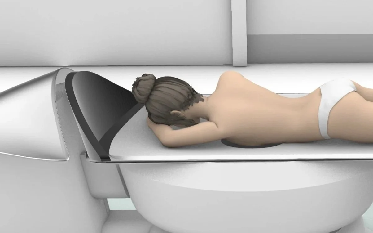 A woman lying face down on a medical device, with her head turned to the side and hands supporting her head.