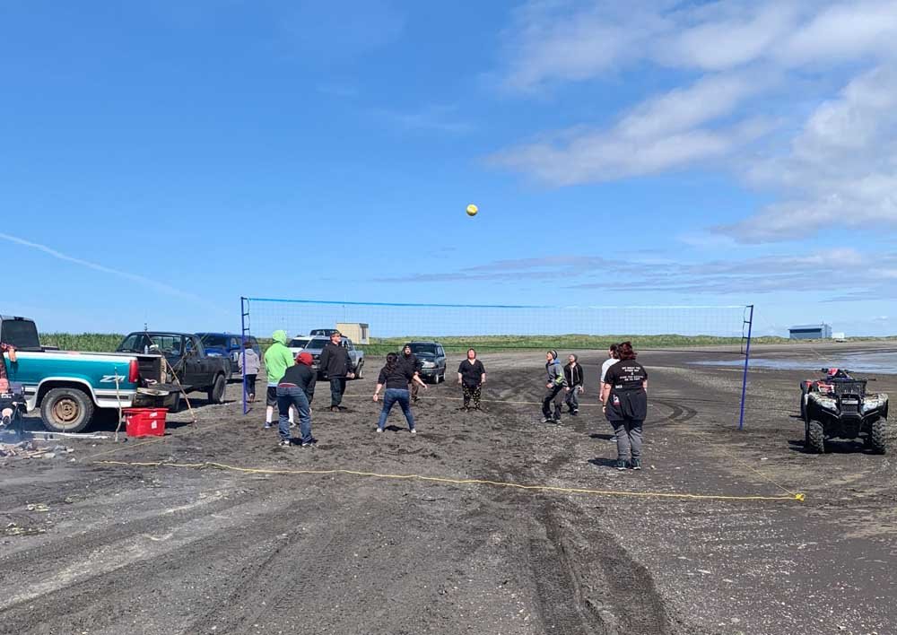 Community members play beach volleyball on a summer day