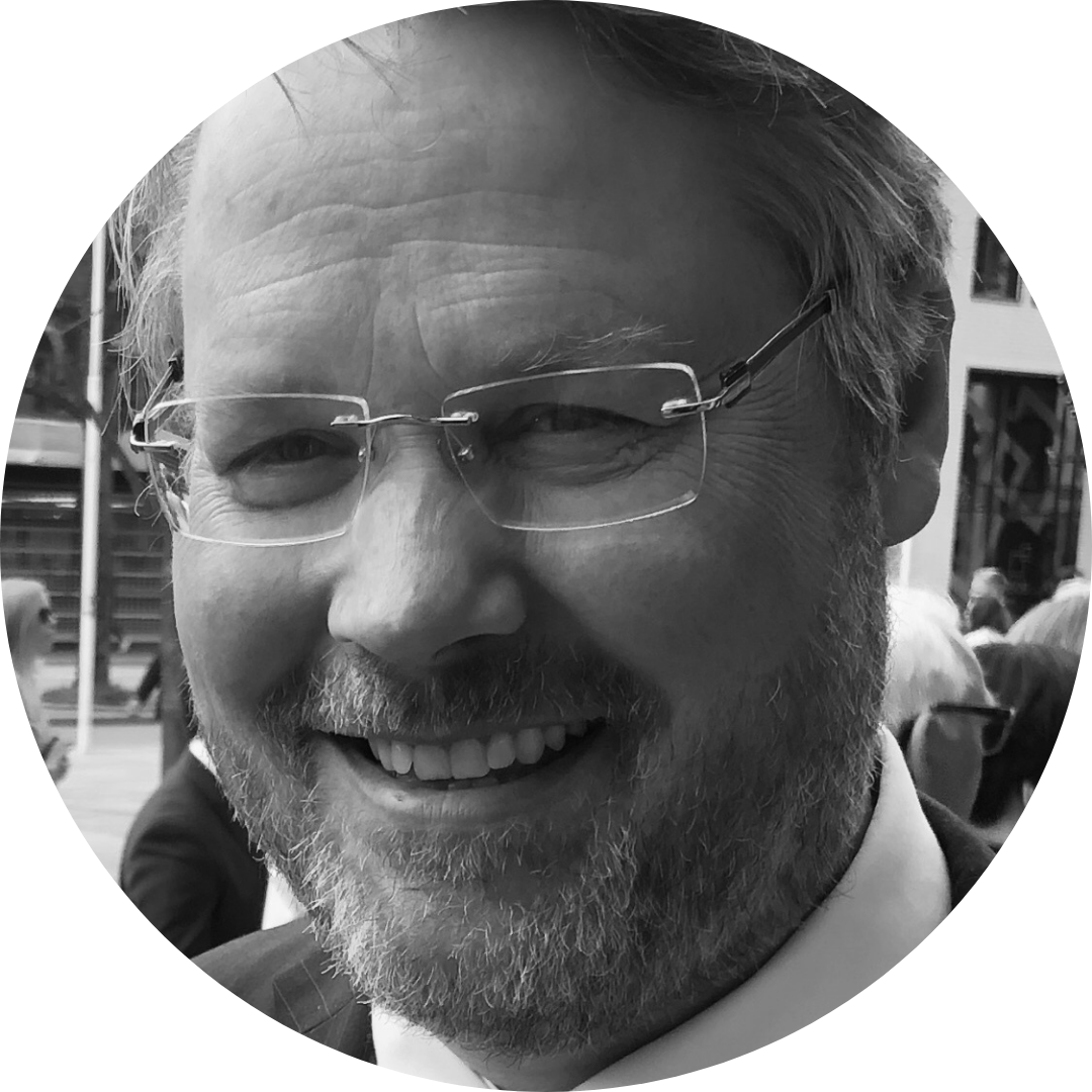 Black and white photo of a smiling young man with short dark hair.