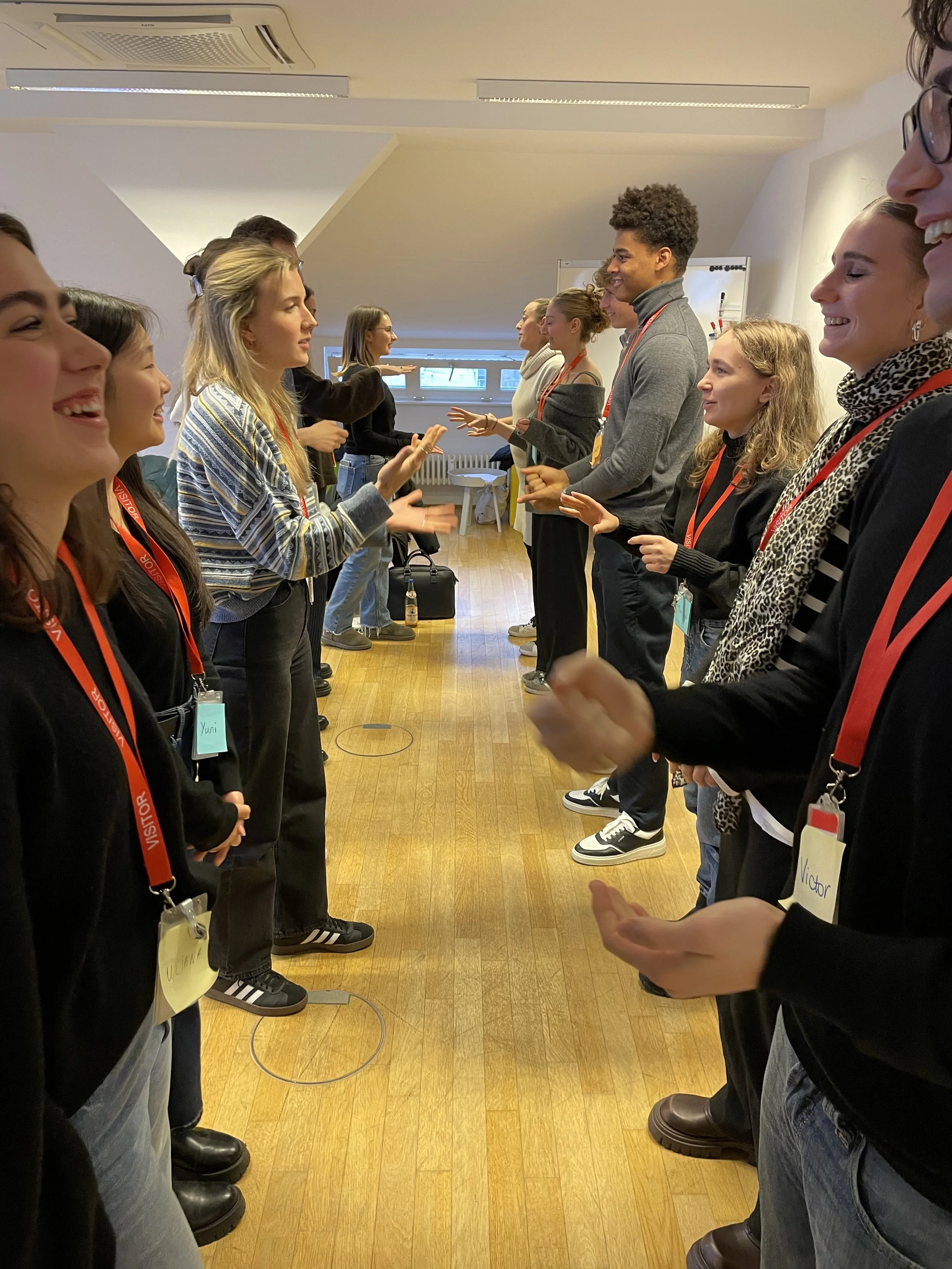 People standing in two lines facing each other, engaging in a team-building activity and ice breaker in workshop setting.