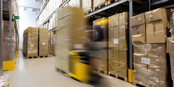 A yellow forklift moving through a warehouse aisle.
