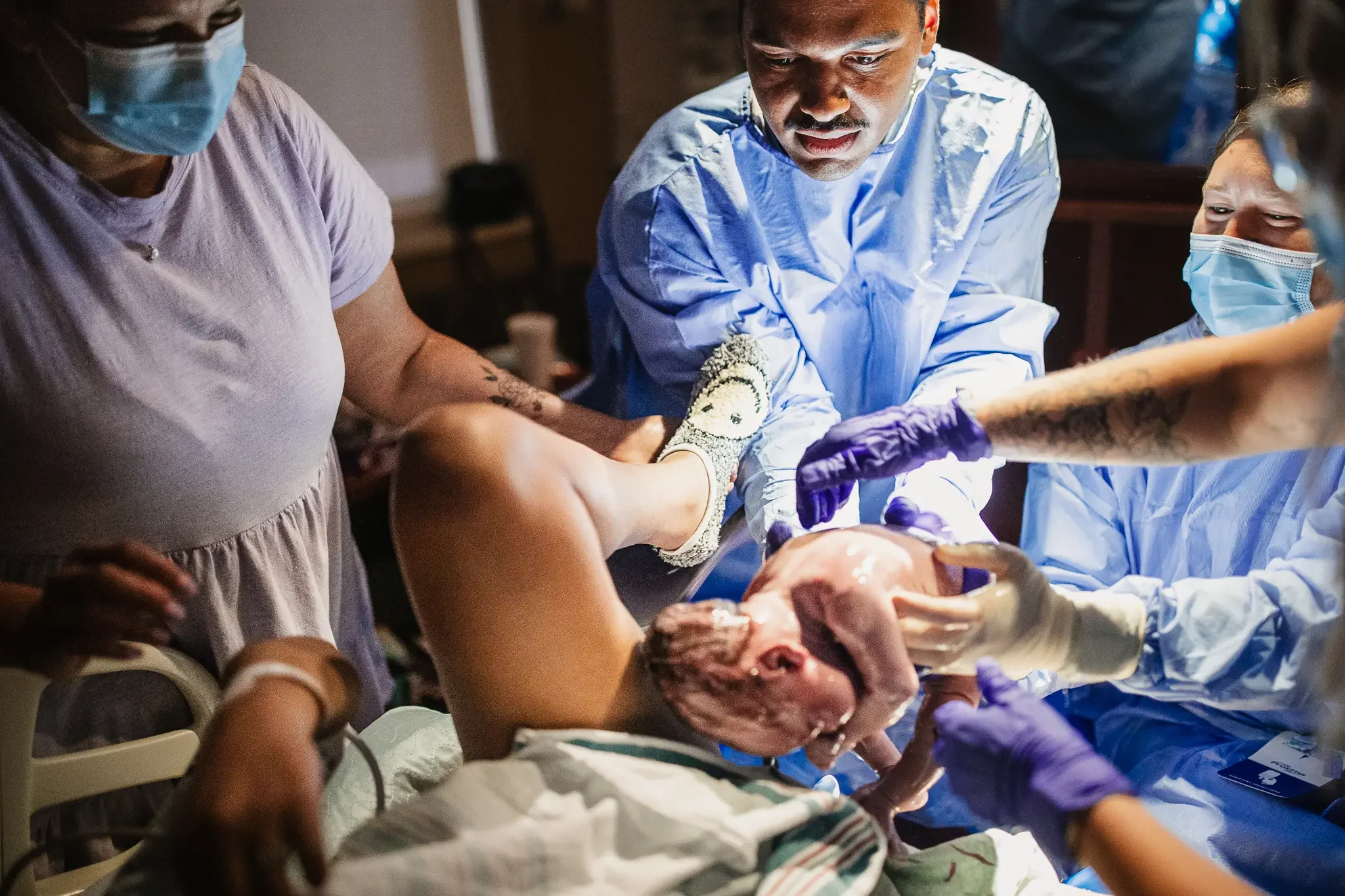 A Black father helps deliver his newborn baby. Grand Rapids Hospital Birth Photography by Brianna Trammell of The Nurturing Company.