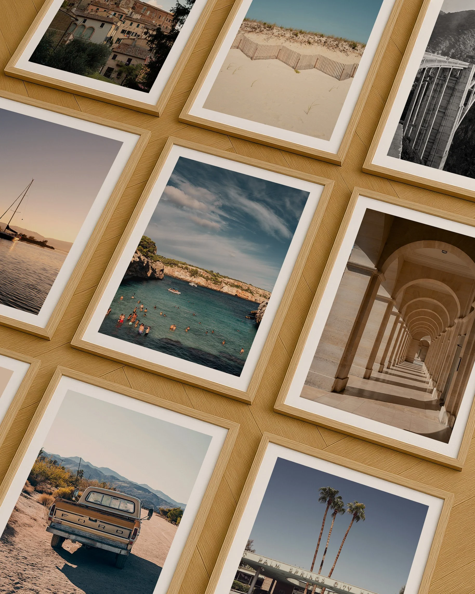 Multiple framed photographs arranged on a wooden surface, showcasing various landscapes and cityscapes including a beach, mountains, a river, and architectural structures.