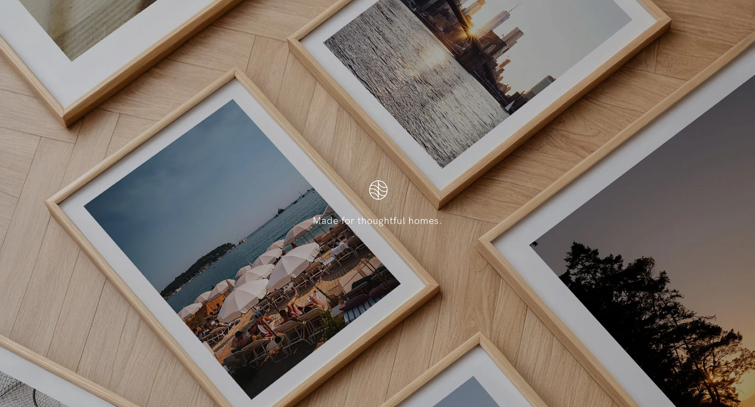 Photographs of outdoor scenes laid out on a wooden surface, including a sunset over a city skyline, a beach with umbrellas and people, and a forest at dusk.