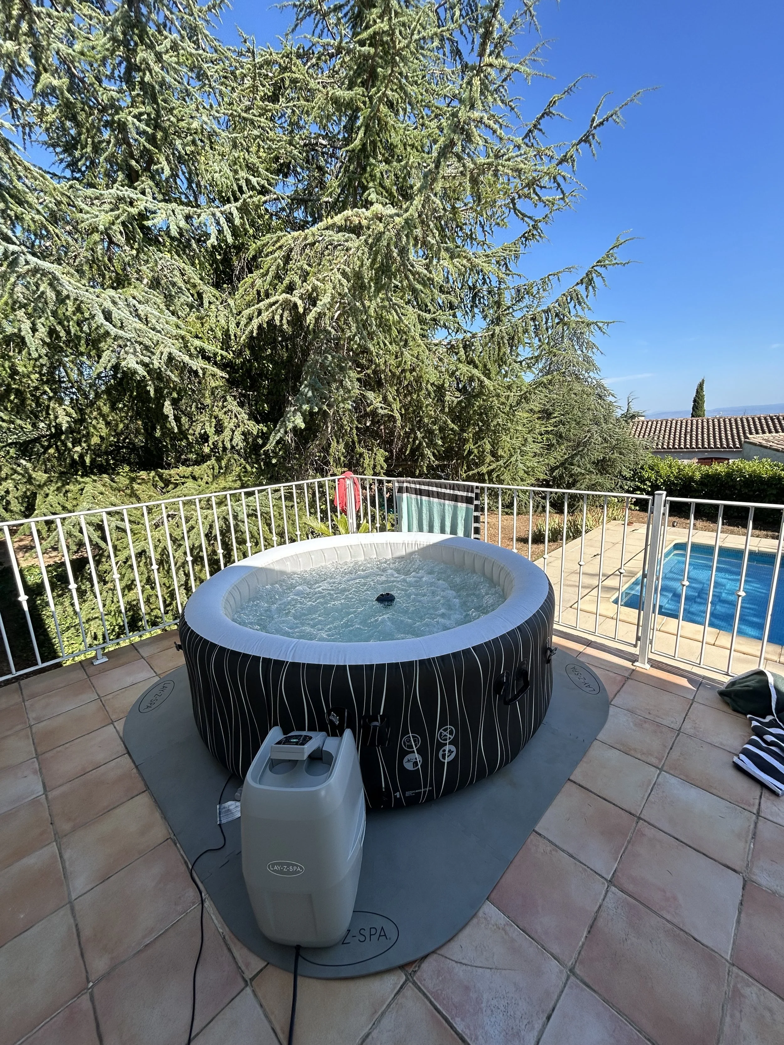 Jacuzzi gonflable bleu illuminé dans l'obscurité, vue vers le ciel étoilé, avec la lune et une étoile filante visible.