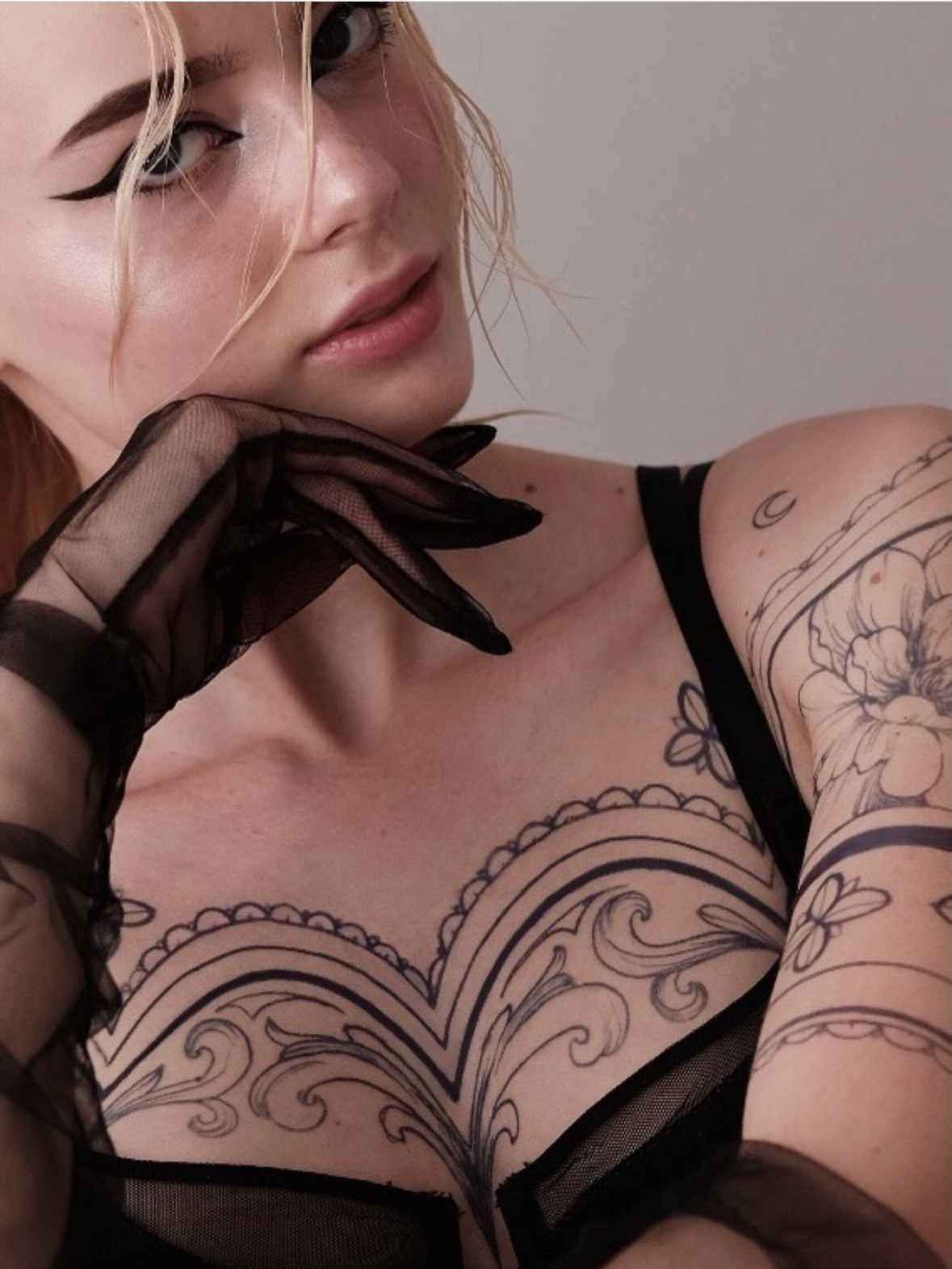 Fine line ornamental chest tattoo with scalloped lace border and baroque filigree, plus floral sleeve by @veronicalilu